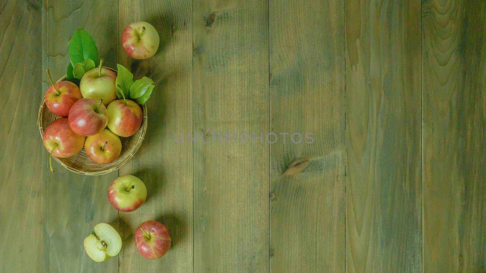 Top view red and yellow apple with leaves and  bamboo basket on wooden background with free space for text
