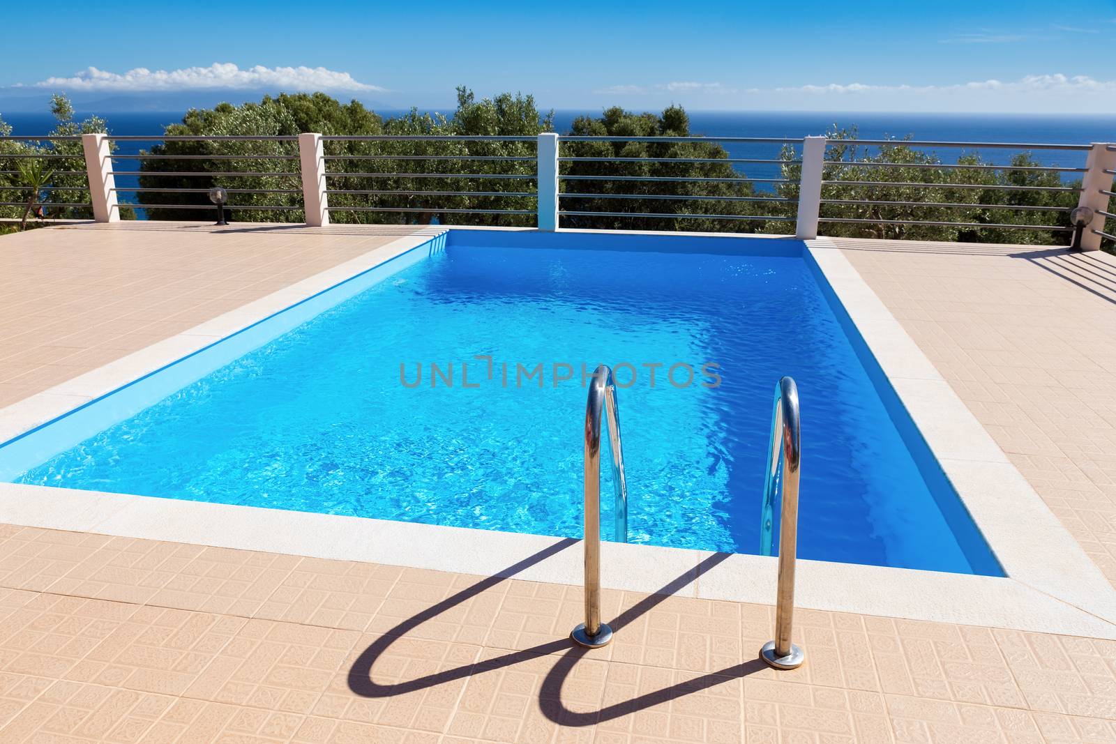 Water in blue swimming pool near sea in greece by BenSchonewille