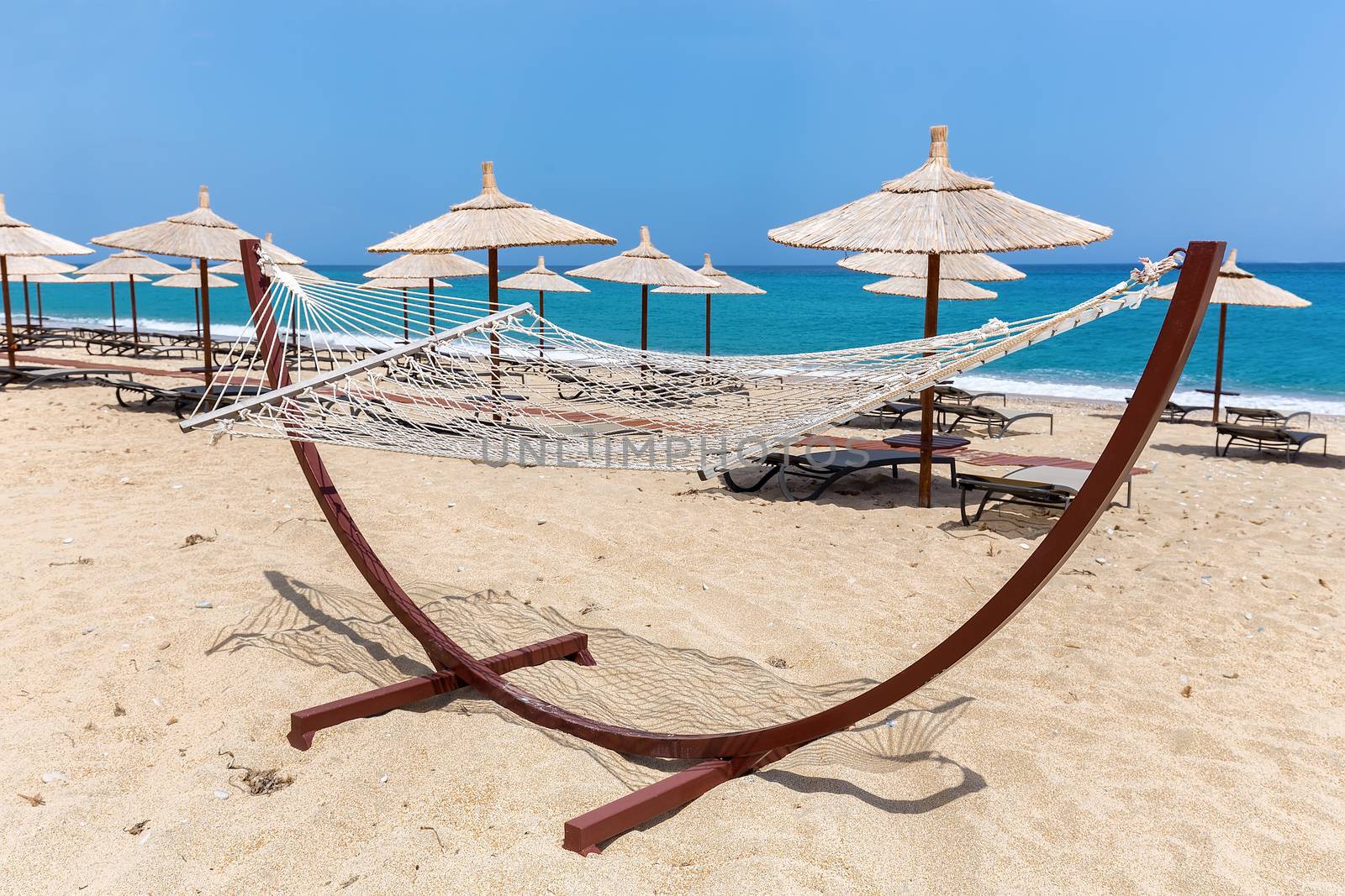 Hammock with beach umbrellas and loungers at greek coast with sea