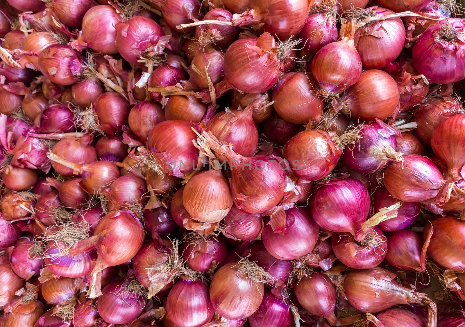 Heap of red onions on market by BenSchonewille