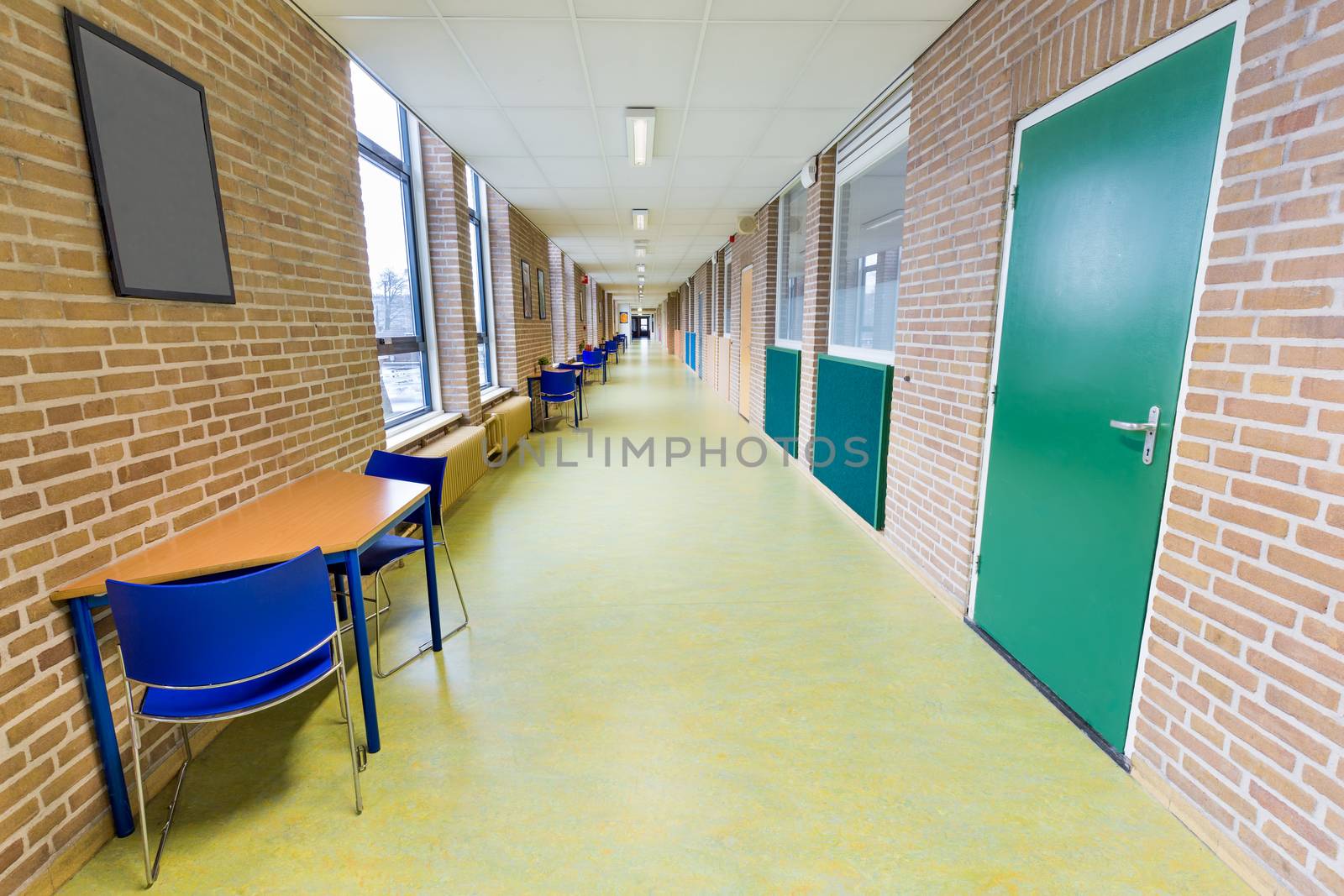 Long empty corridor in college school building by BenSchonewille