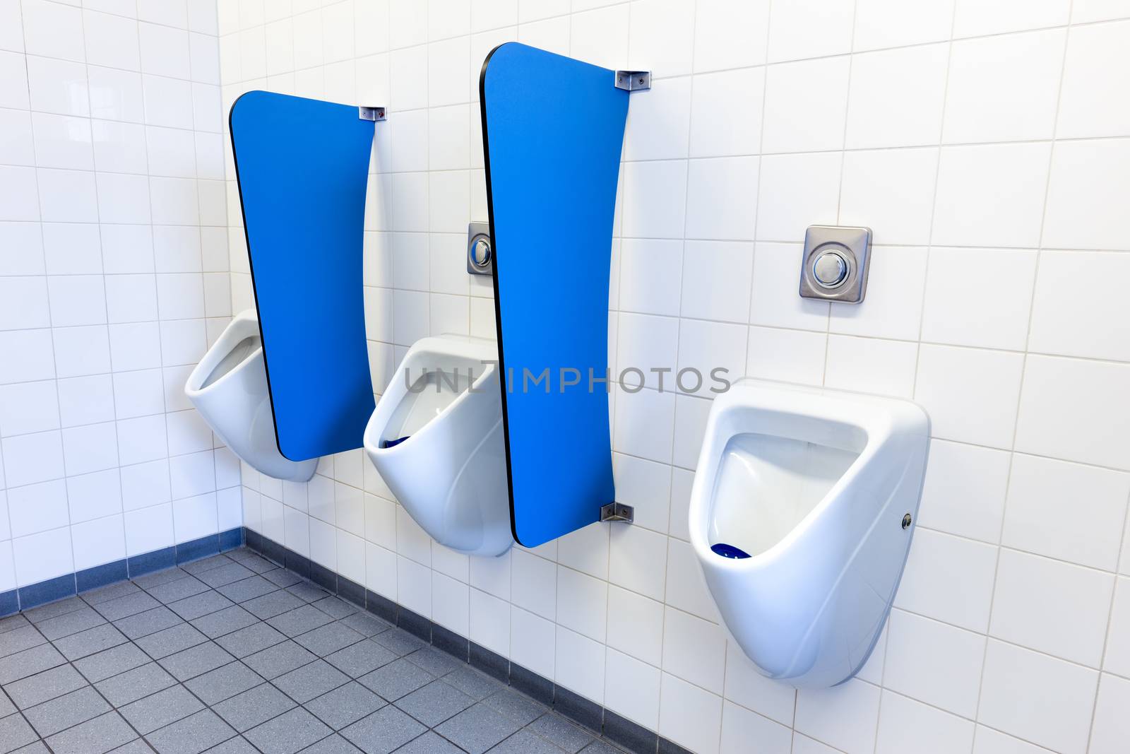 Men's urinals on white wall with blue partitions by BenSchonewille