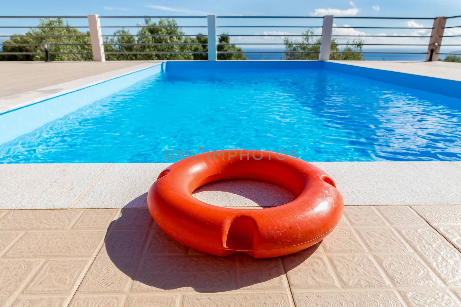 Orange life buoy lying at blue swimming pool in Greece