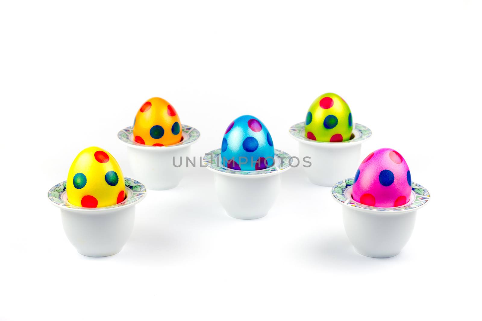 Painted easter eggs standing in porcelain egg cups on white by BenSchonewille