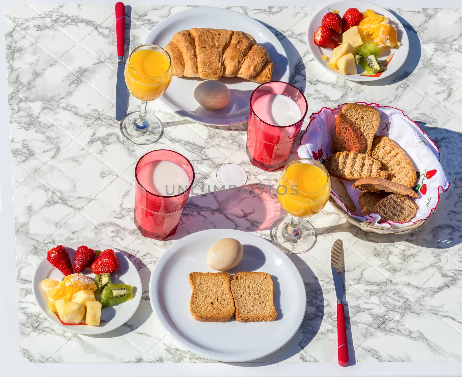 Set table with various food and drink for breakfast on sunny day in summer season