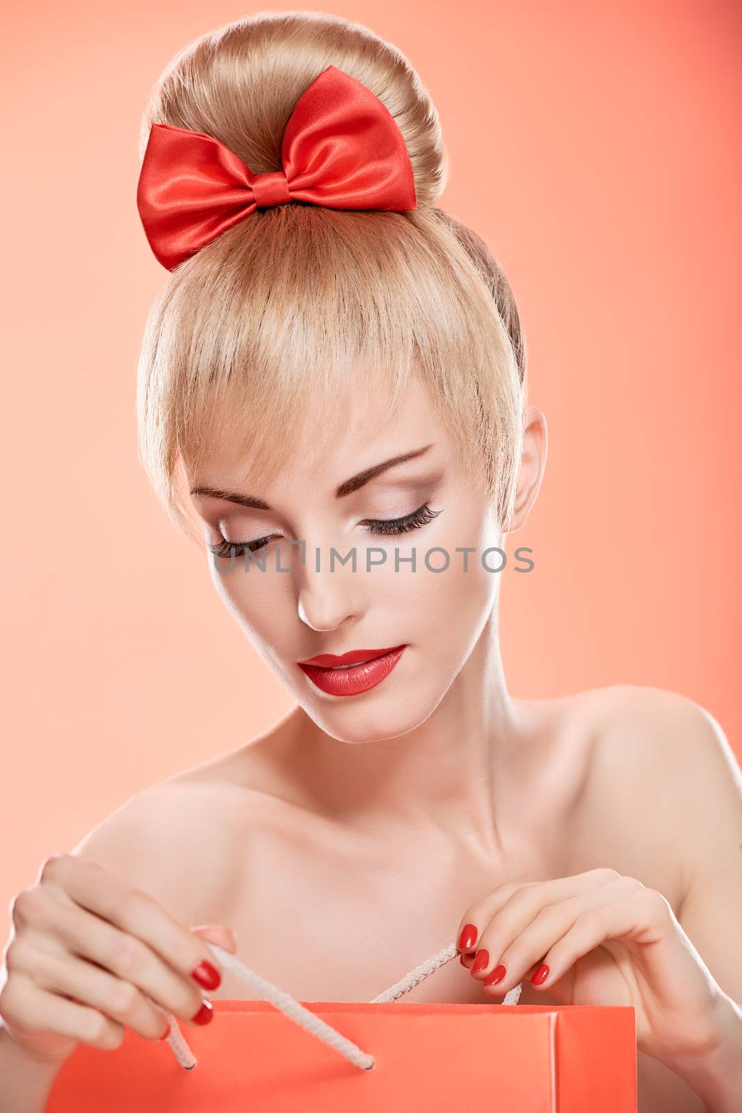 Beauty fashion portrait loving woman surprised looking into shopping bag. Confidence sensual attractive pretty nude blonde sexy girl, Pinup hairstyle, red bow.Unusual playful. Romantic, sale, discount