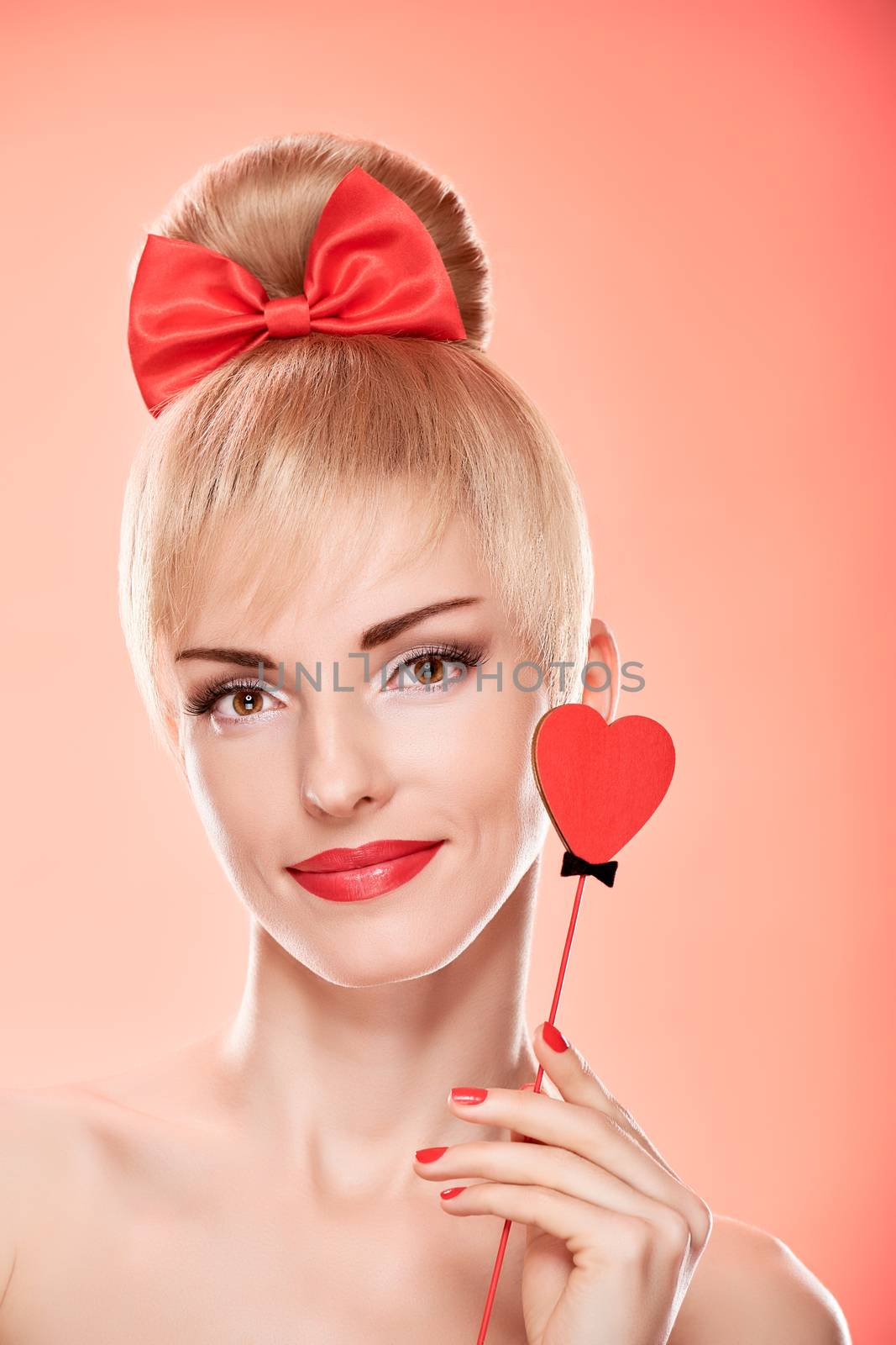 Beauty fashion portrait woman smiling with red heart. Valentines Day, love. Sensual attractive pretty nude blonde sexy girl, Pinup hairstyle, bow. Unusual emotional playful. Romantic, retro vintage 
