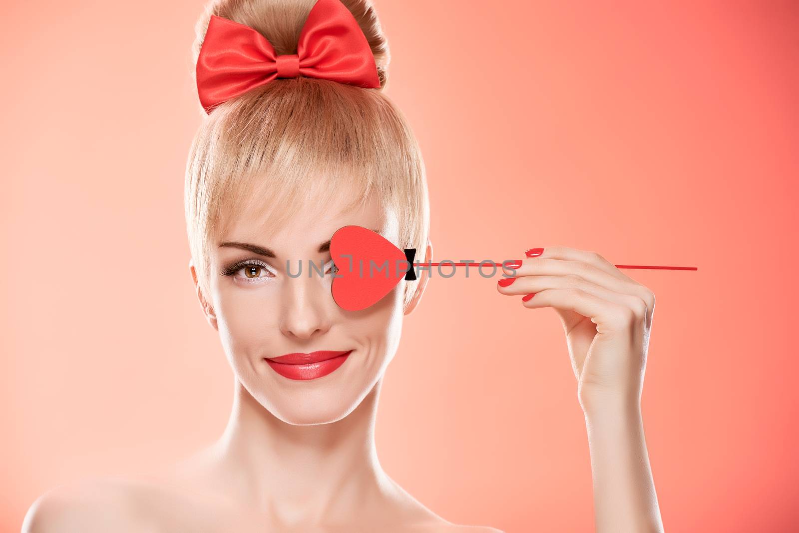 Beauty fashion portrait woman smiling with red heart. Valentines Day, love. Sensual attractive pretty nude blonde sexy girl, Pinup hairstyle, bow. Unusual emotional playful. Romantic, retro vintage 