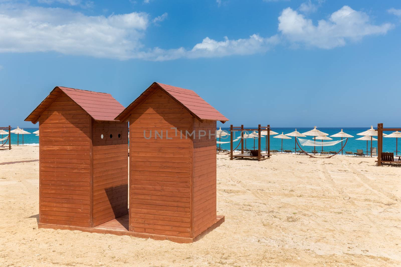 Two wooden beach huts with umbrellas on  sandy shore in Greece