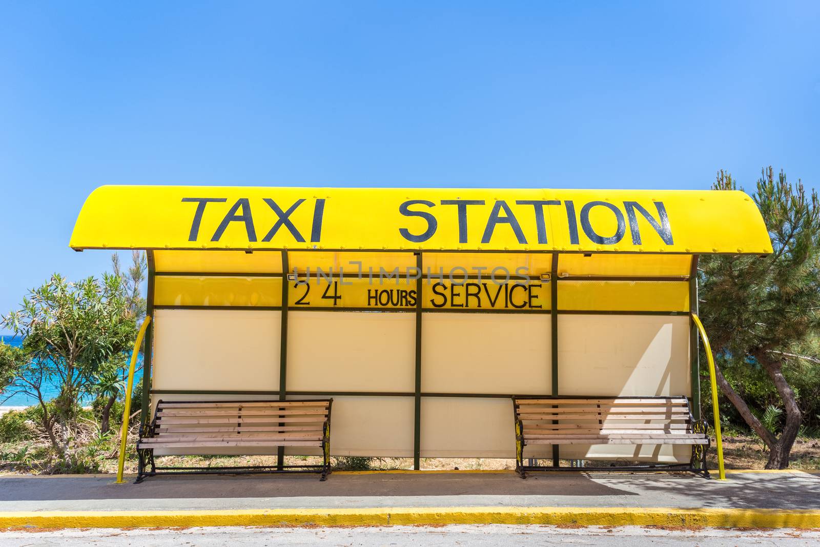 Yellow taxi station at coast in Greece by BenSchonewille