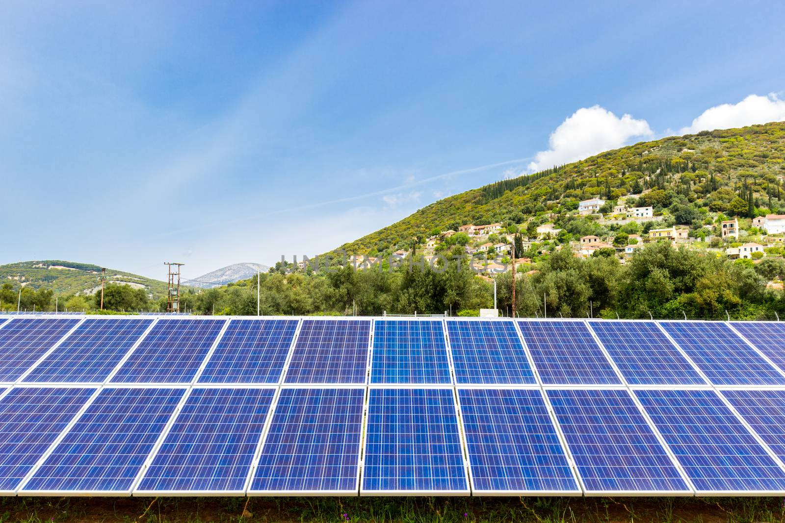 Row of blue solar collectors near greek town on mountain