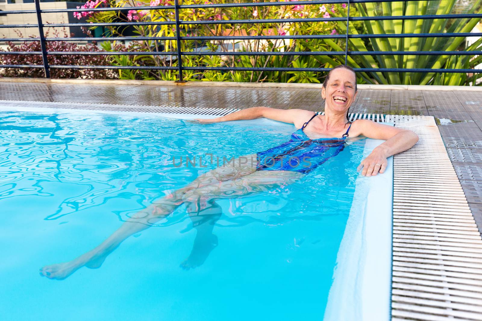 Dutch middle aged woman relaxing lying in swimming pool