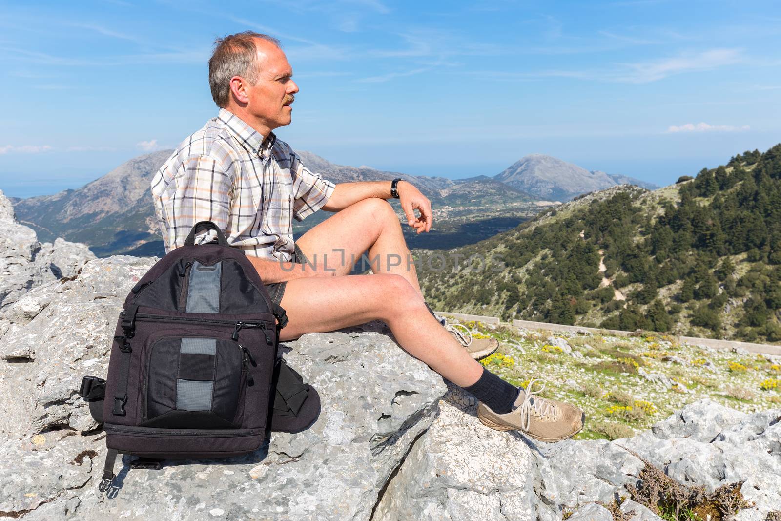 Caucasian man sitting with backpack in greek mountains by BenSchonewille