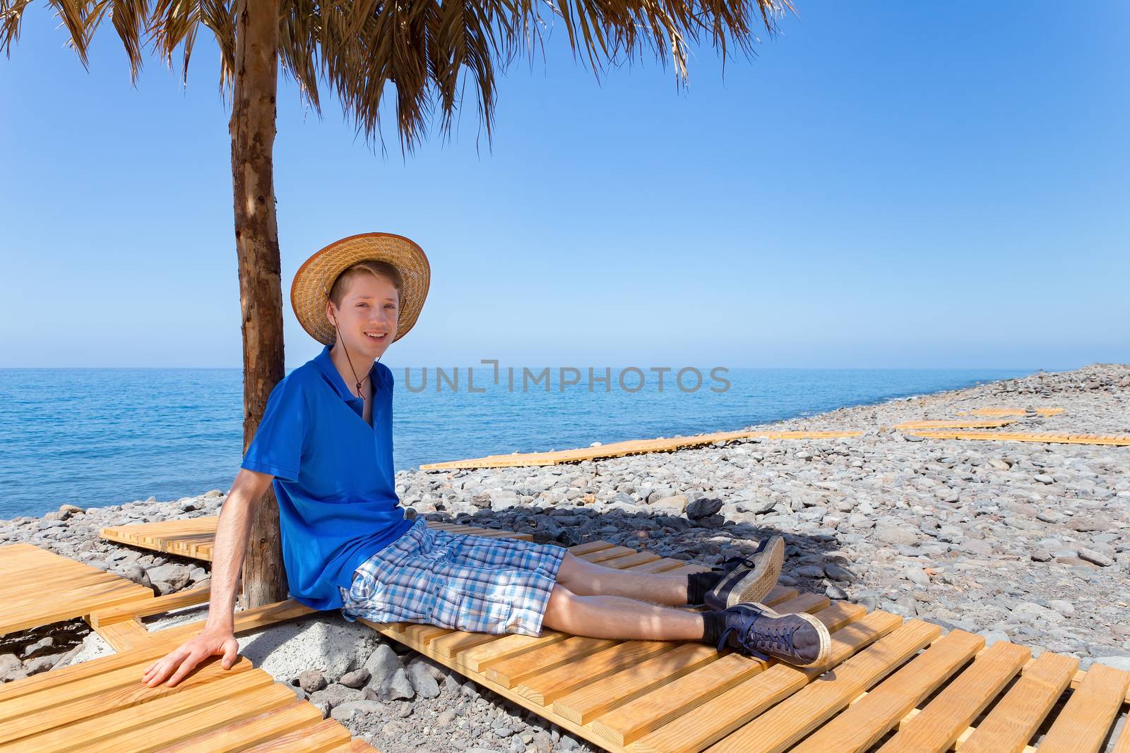 Dutch boy sitting under parasol on portuguese beach by BenSchonewille
