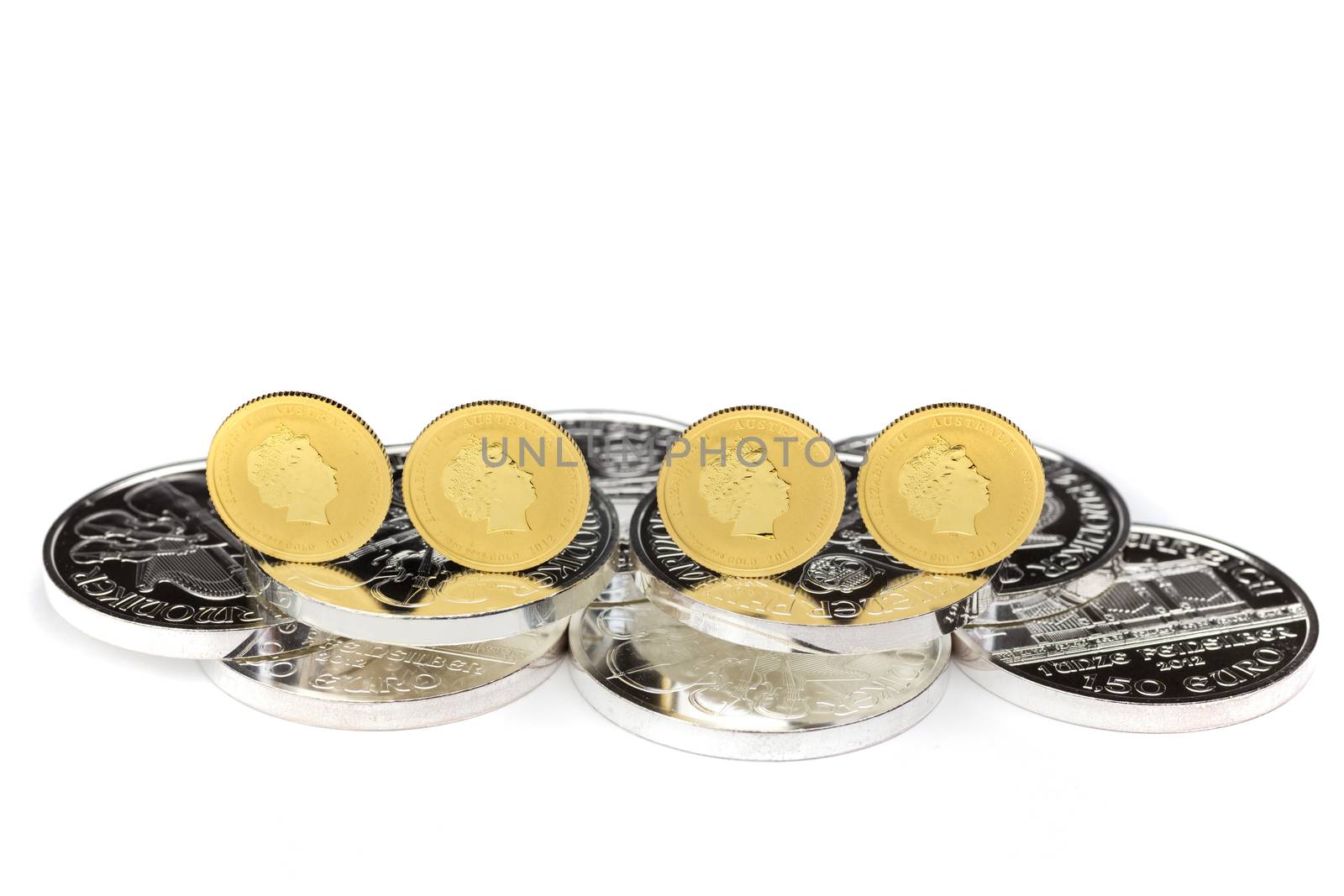 Four gold coins standing on silver coins isolated on white background