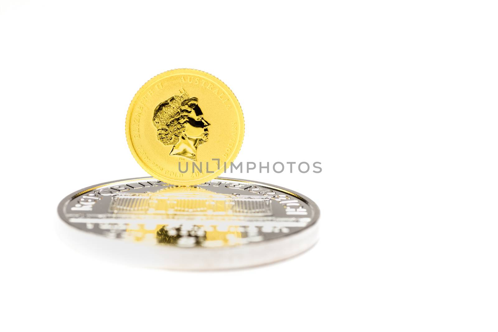 Golden dollars coin standing on silver bullion isolated on white background