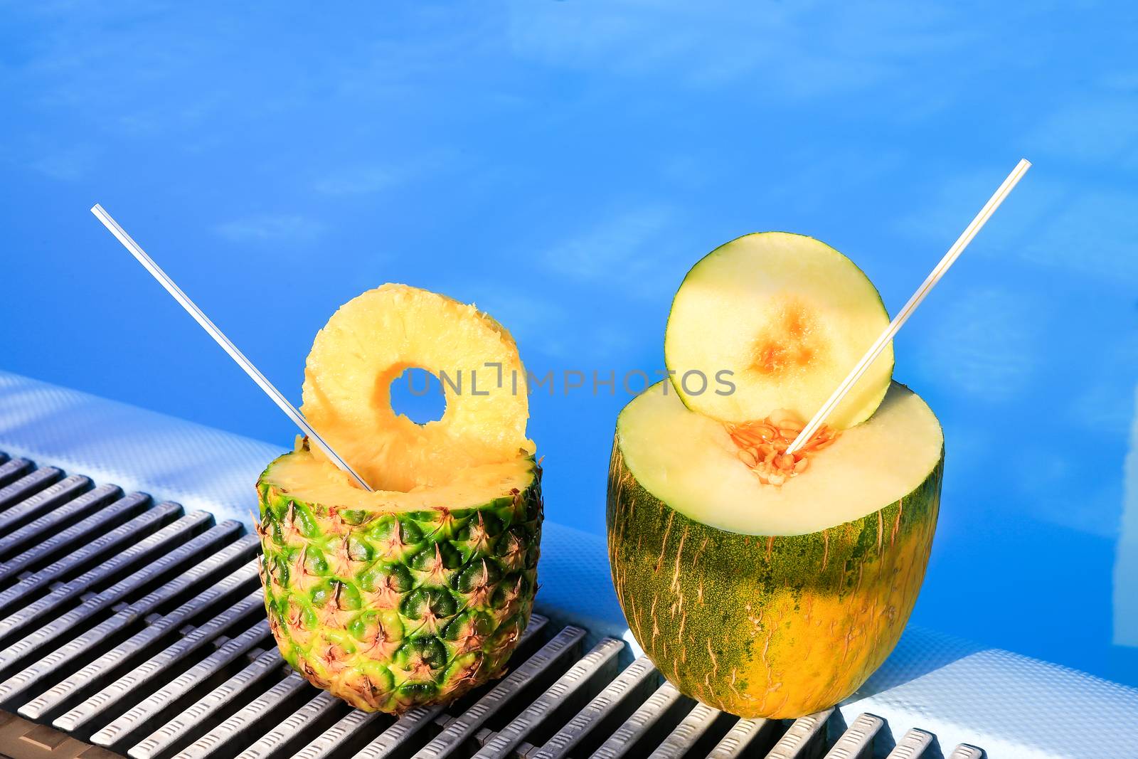 Pineapple and melon fruit with straws at swimming pool by BenSchonewille
