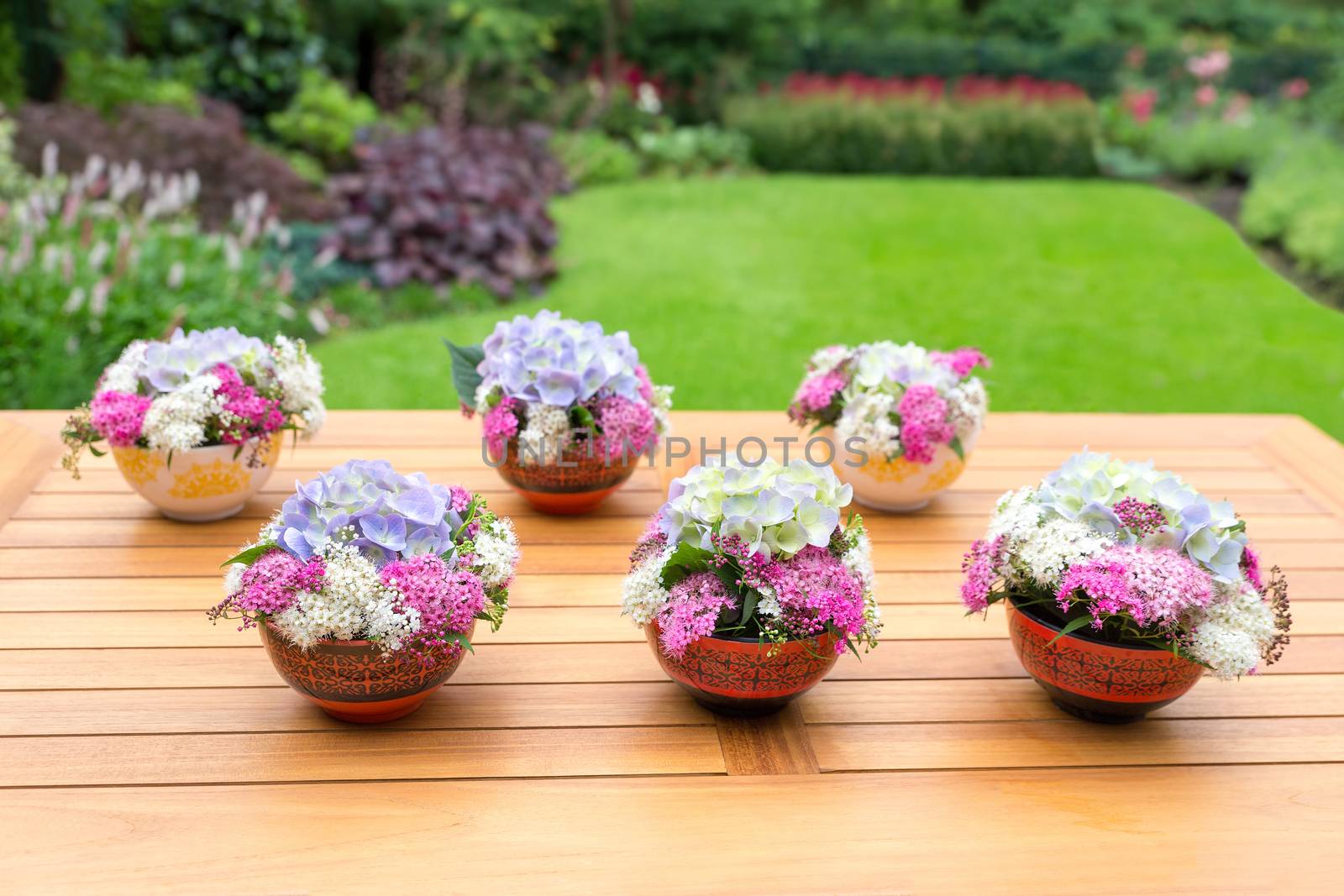 Vases with blooming flowers on teak table by BenSchonewille