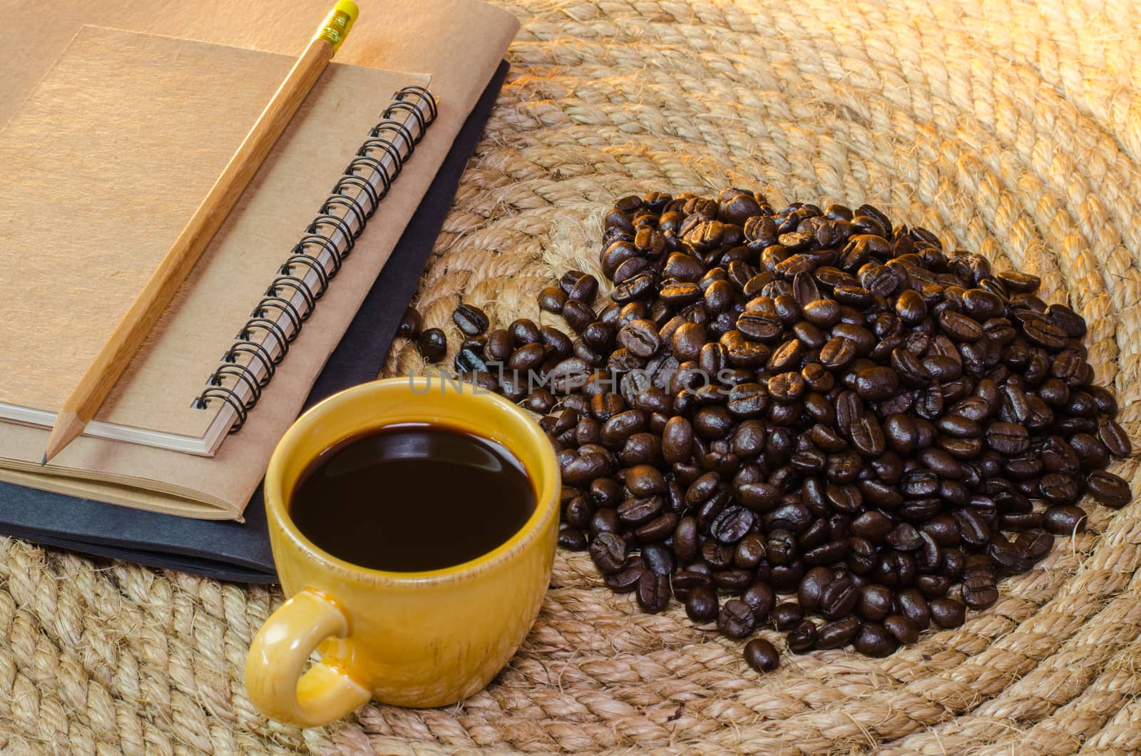 Cup of coffee with  notebook on a jute rope.