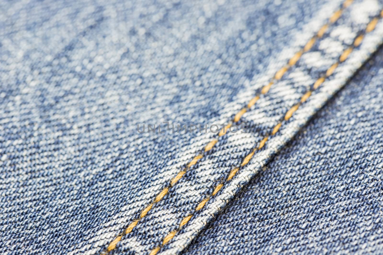 Blue denim with yellow stitching as background picture
