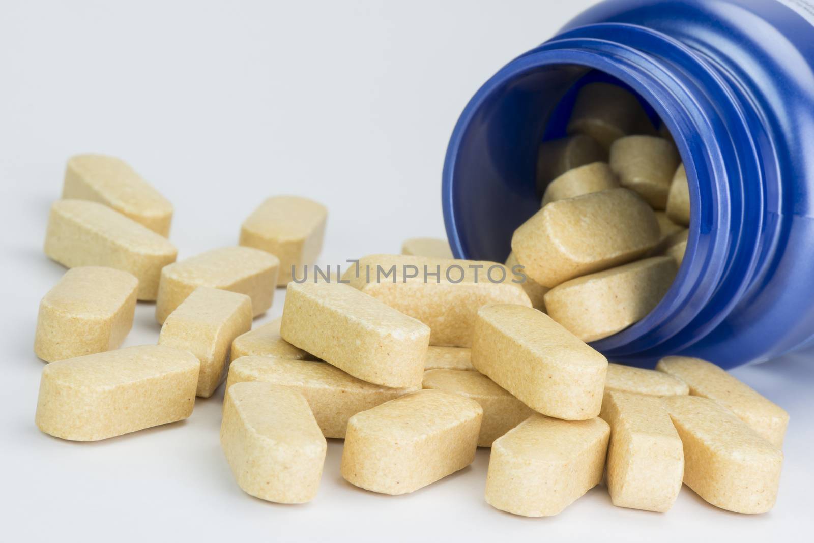 Collection yellow tablets from a fallen blue medicine jar
