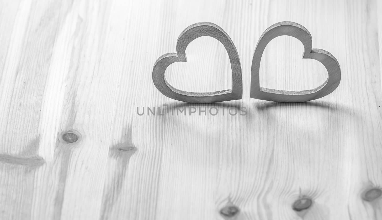 Valentine's holiday settings with two gray wooden hearts on wooden surface.