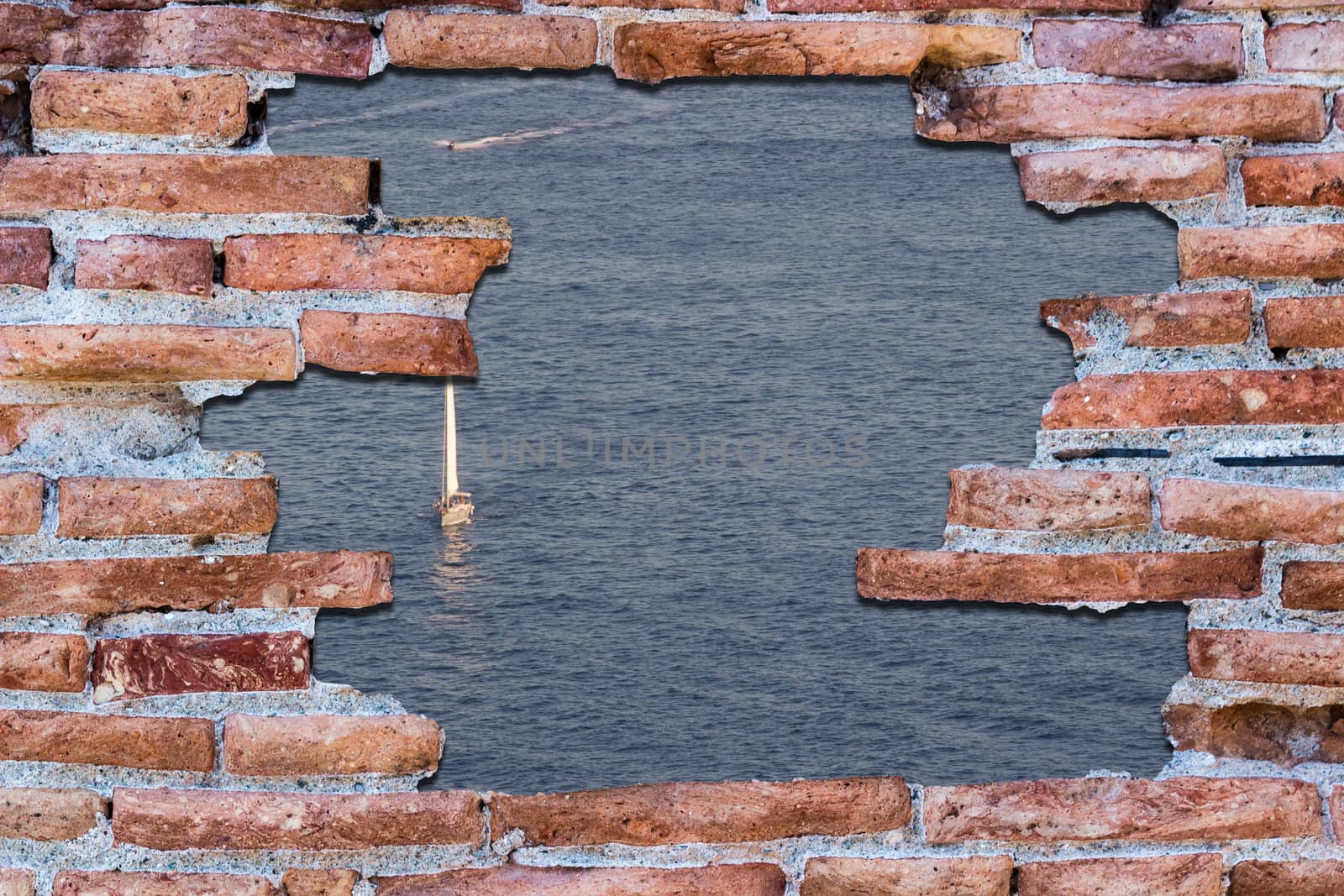 Ancient red brick wall with a hole over the blue sea with sailboat.