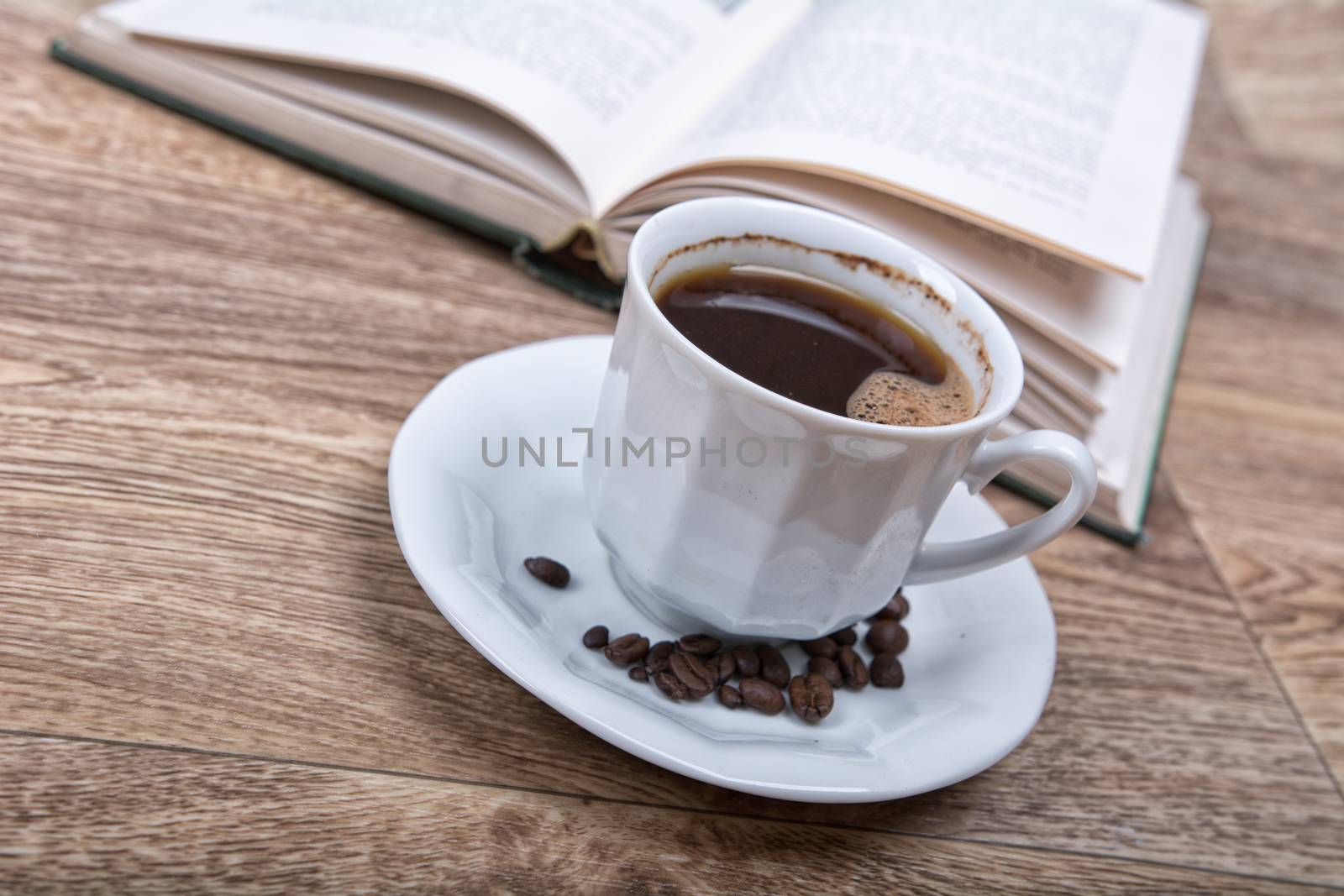 A cup of coffee with a book on a wooden background