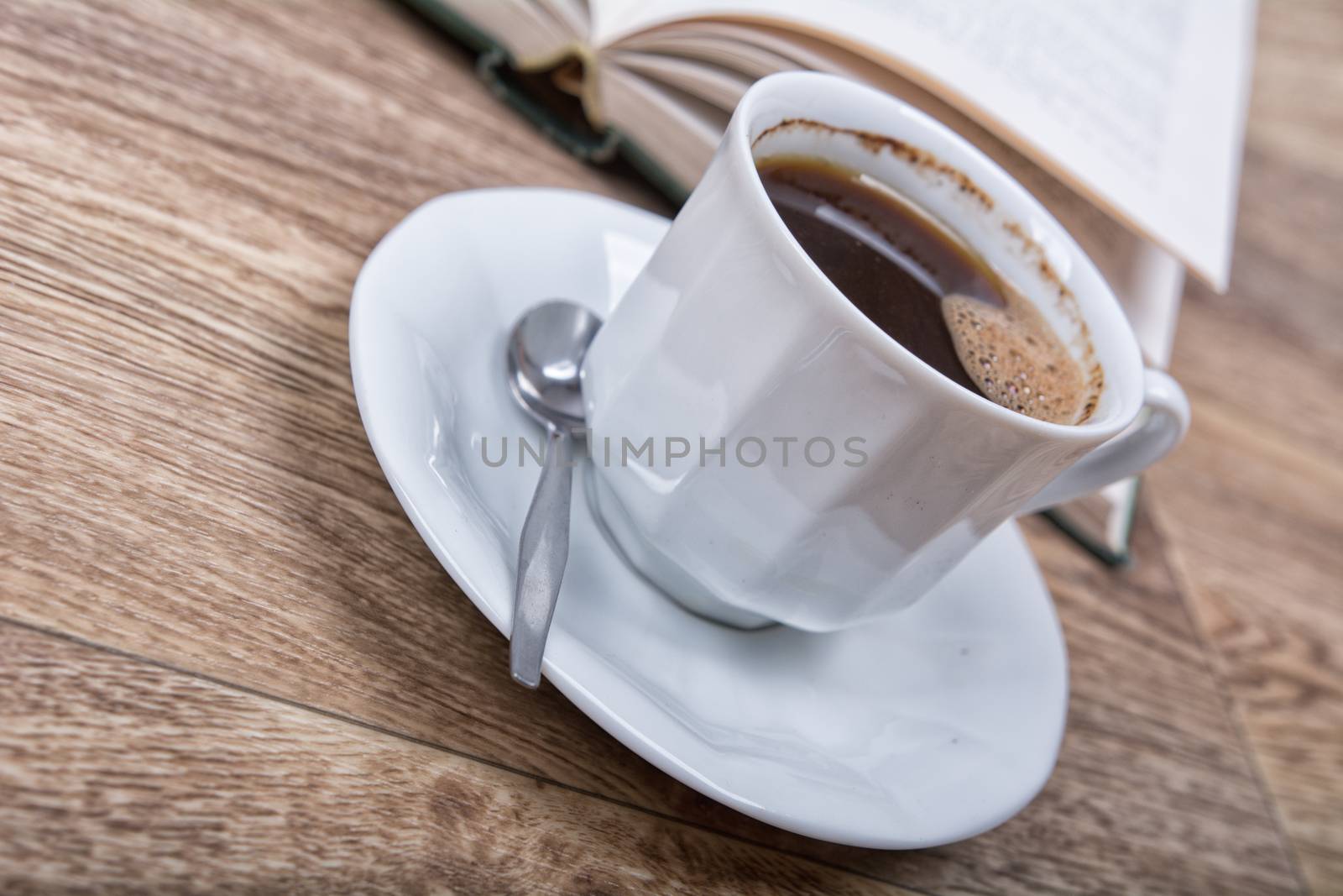 A cup of coffee with a book on a wooden background