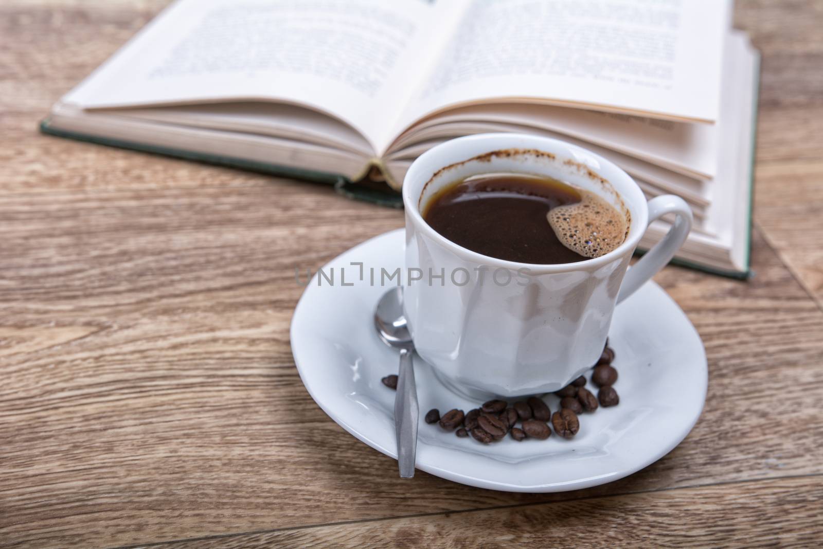 A cup of coffee with a book on a wooden background