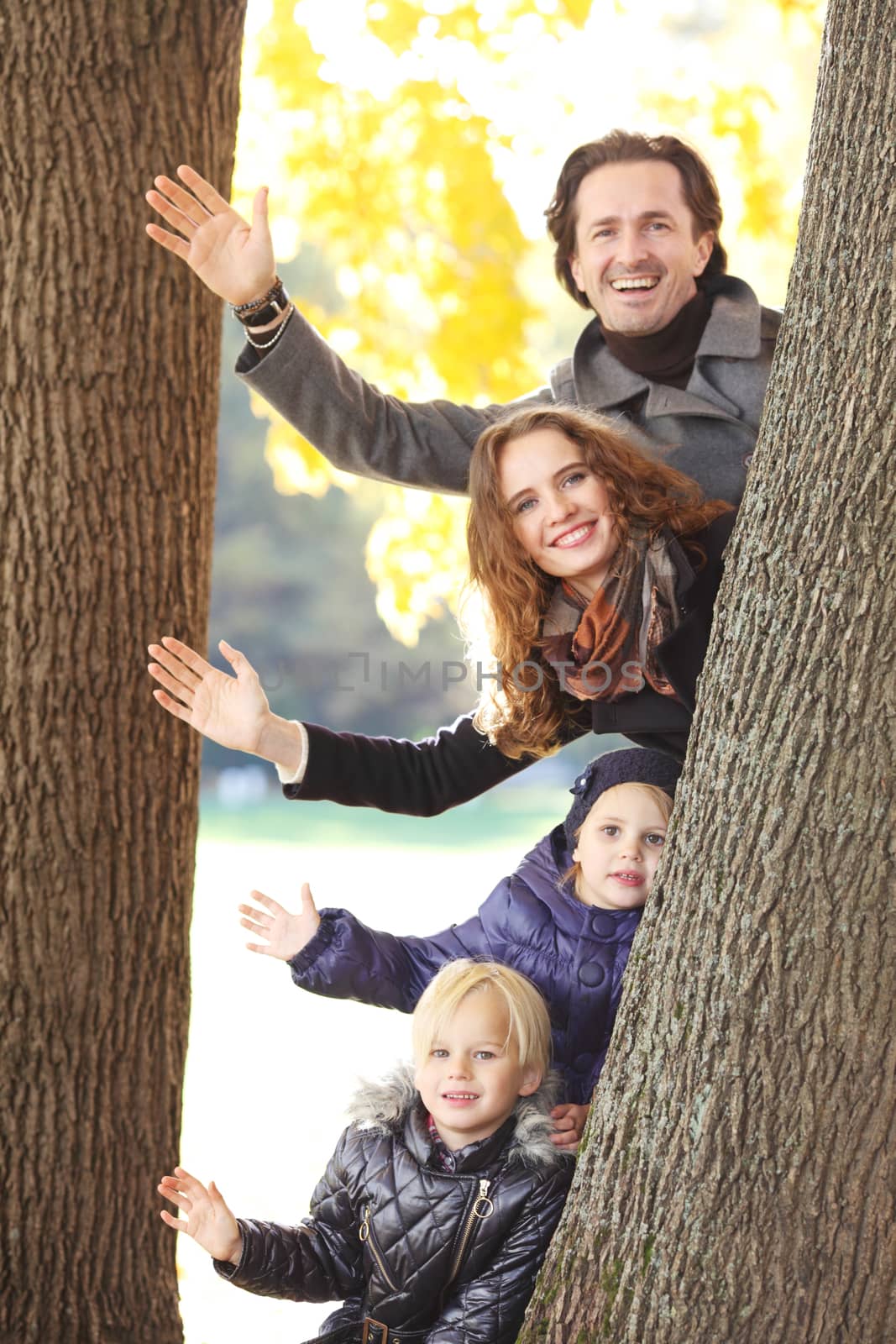 Happy family in autumn park near big tree trunk