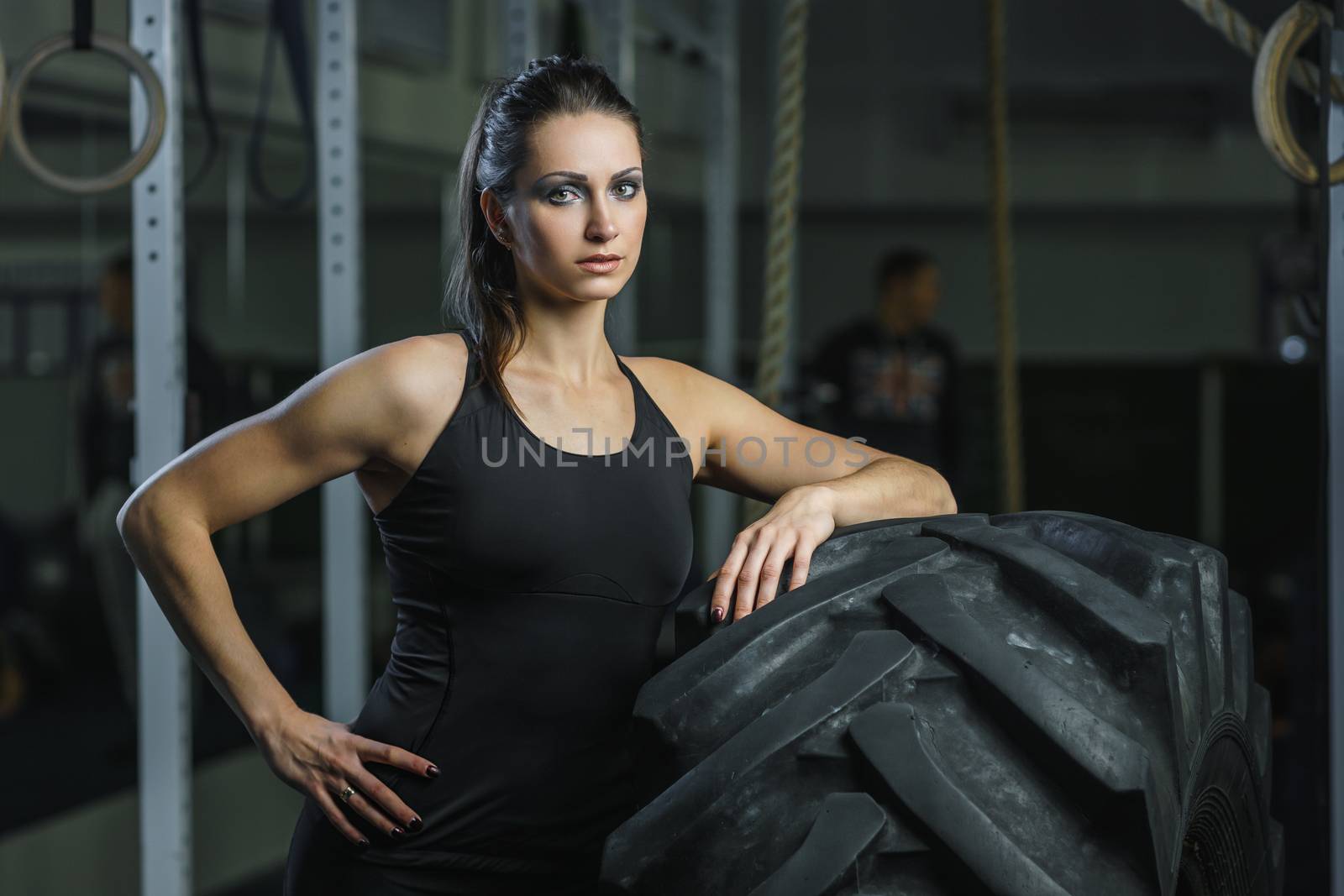 Concept: power, strength, healthy lifestyle, sport. Powerful attractive muscular woman CrossFit trainer doing giant tire workout at the gym