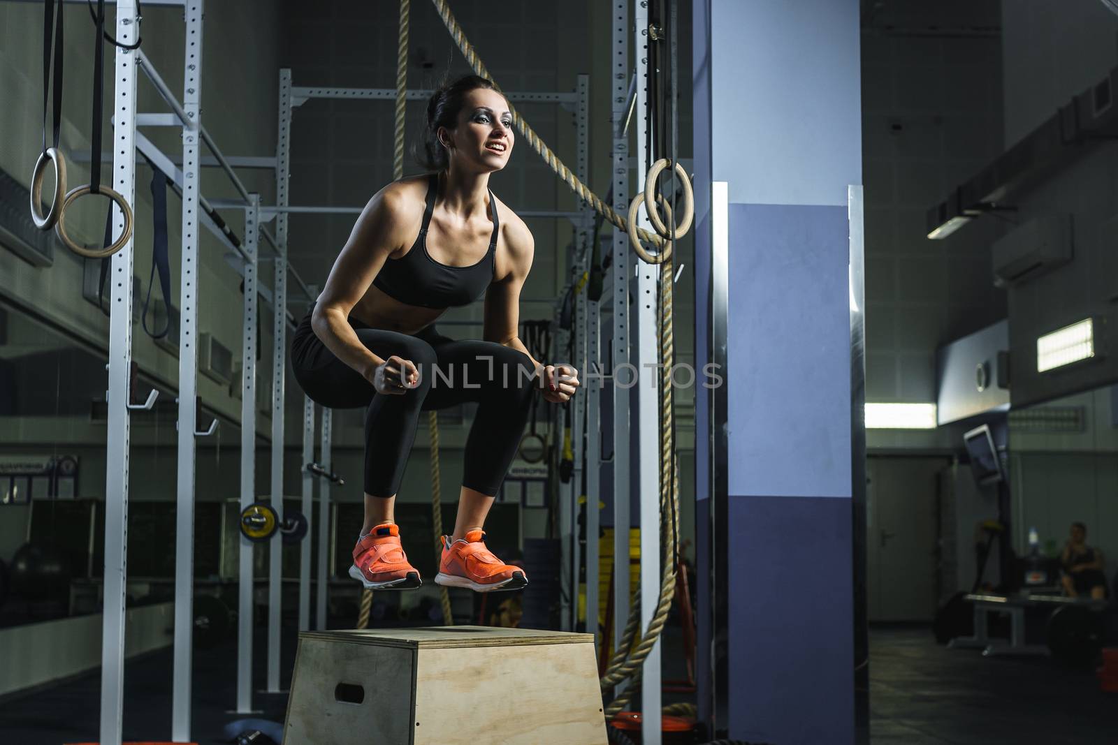 Powerful muscular woman CrossFit trainer jumps during workout at gym by mrakor