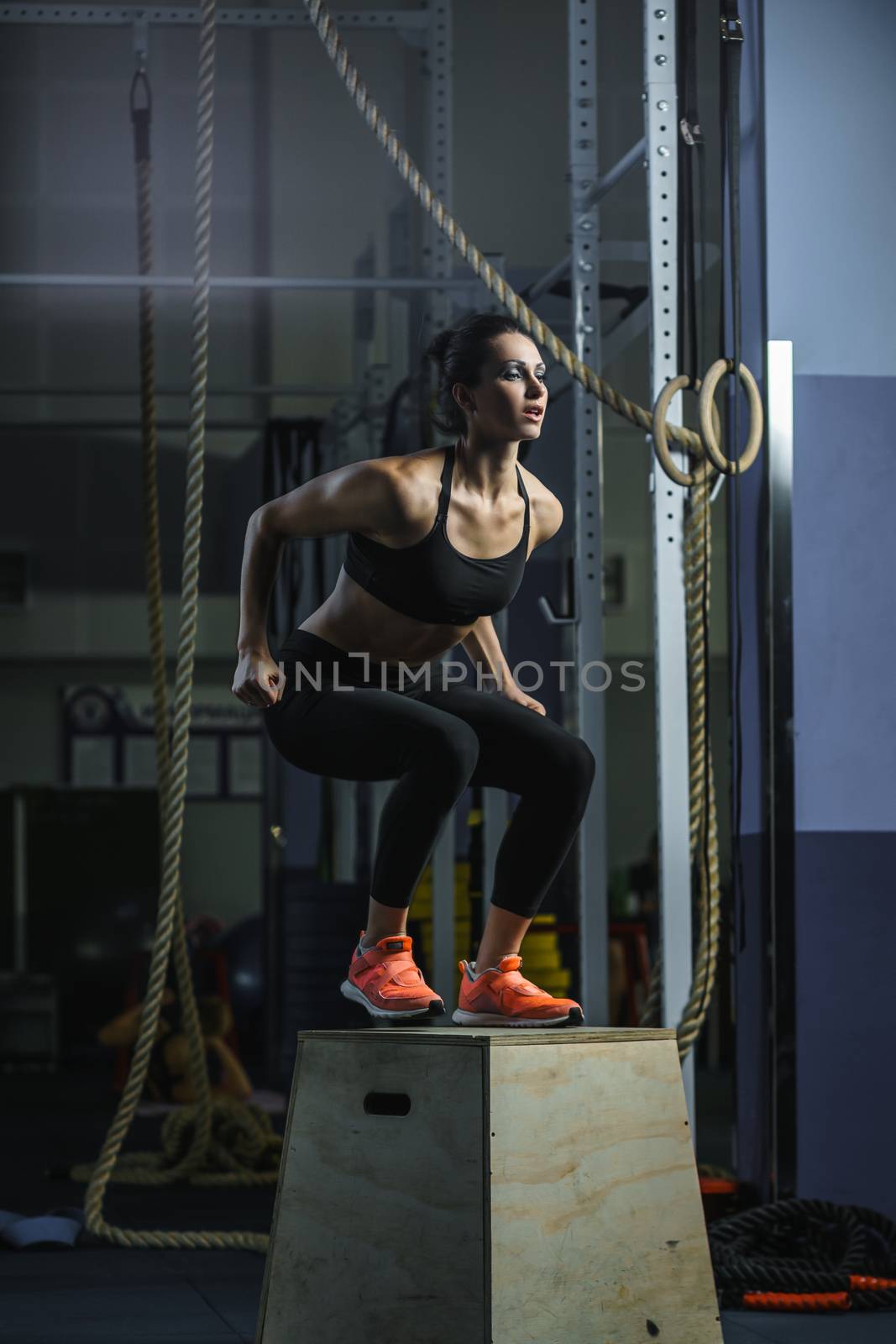 Powerful muscular woman CrossFit trainer jumps during workout at gym by mrakor