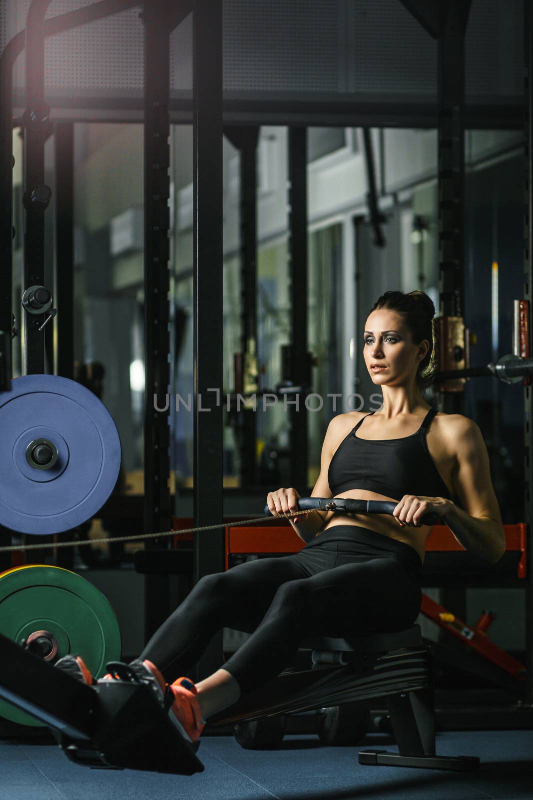 Concept: power, strength, healthy lifestyle, sport. Powerful attractive muscular woman CrossFit trainer do workout on indoor rower at the gym