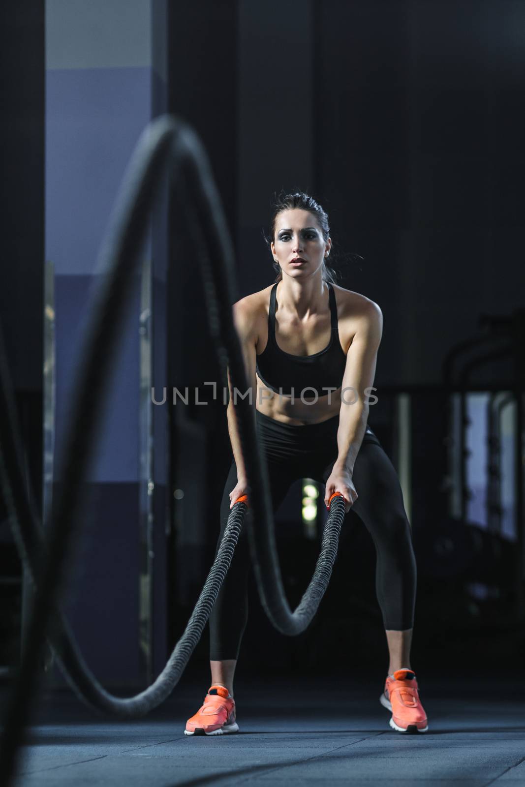 Powerful attractive muscular CrossFit trainer do battle workout with ropes by mrakor