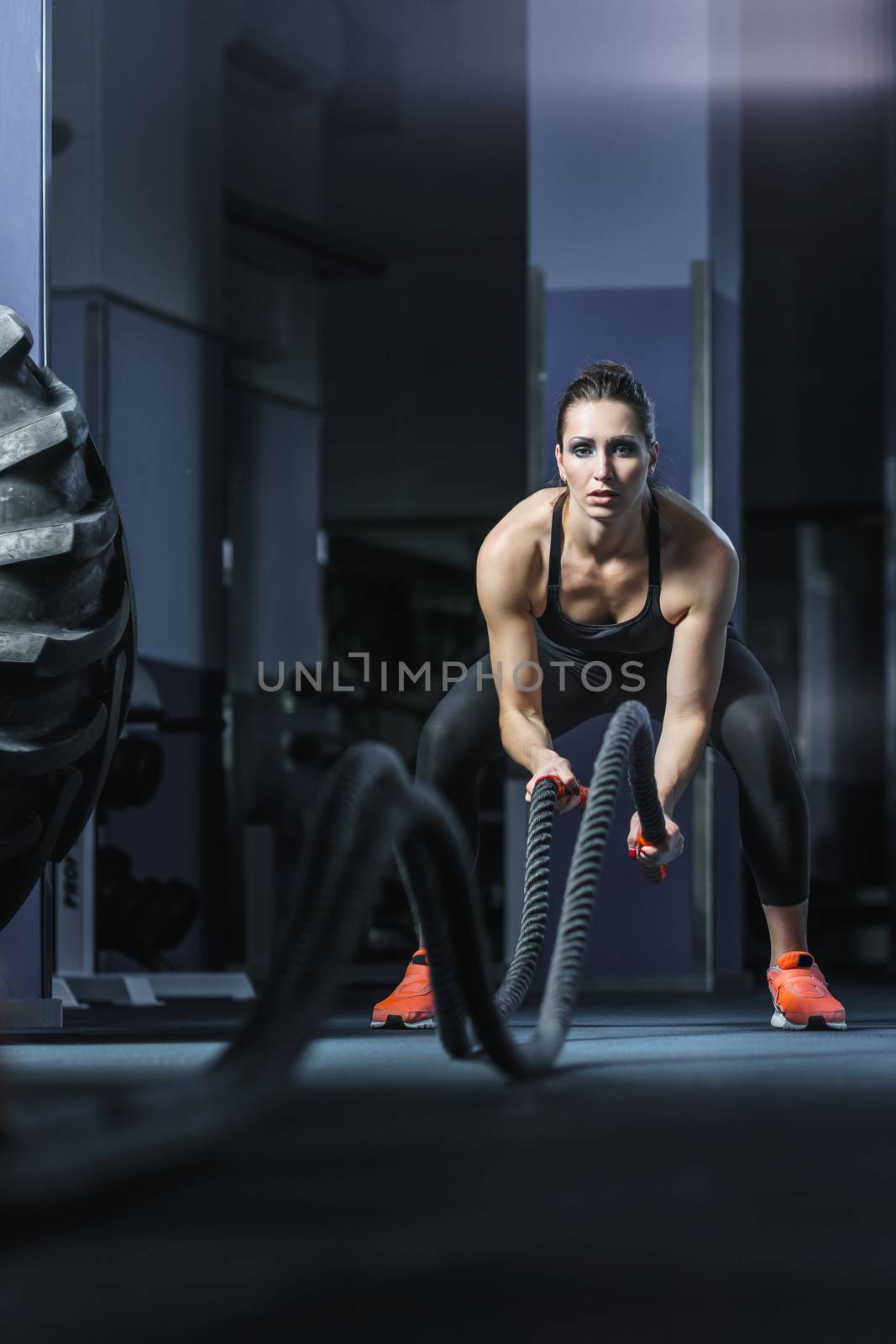 Concept: power, strength, healthy lifestyle, sport. Powerful attractive muscular woman CrossFit trainer do battle workout with ropes at the gym