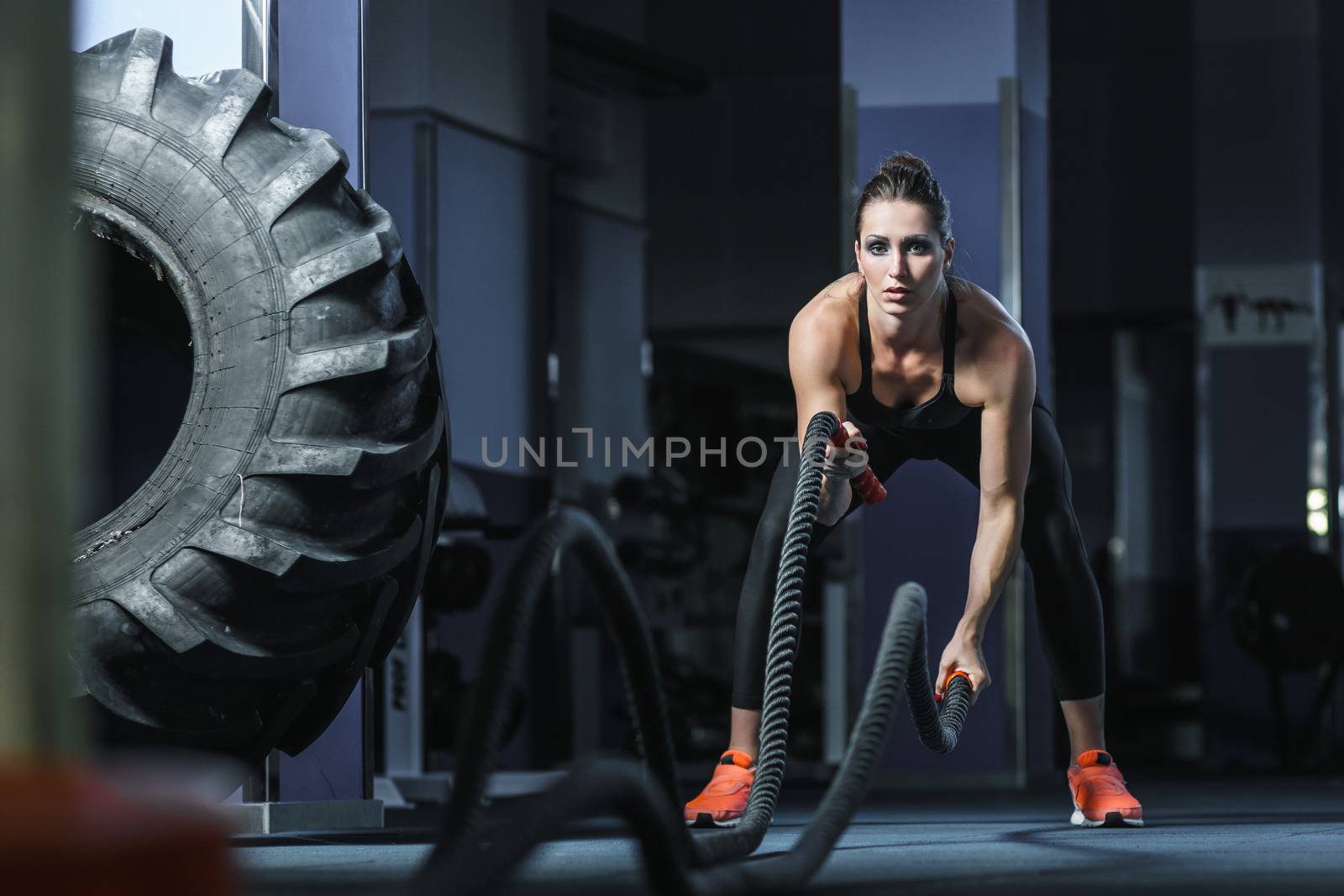 Concept: power, strength, healthy lifestyle, sport. Powerful attractive muscular woman CrossFit trainer do battle workout with ropes at the gym