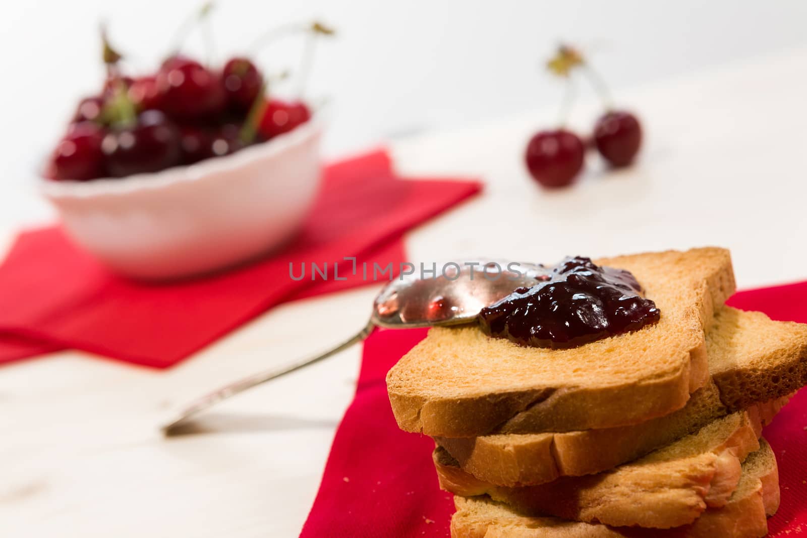 Closeup of rusk with cherry jam and cherry fruit on background