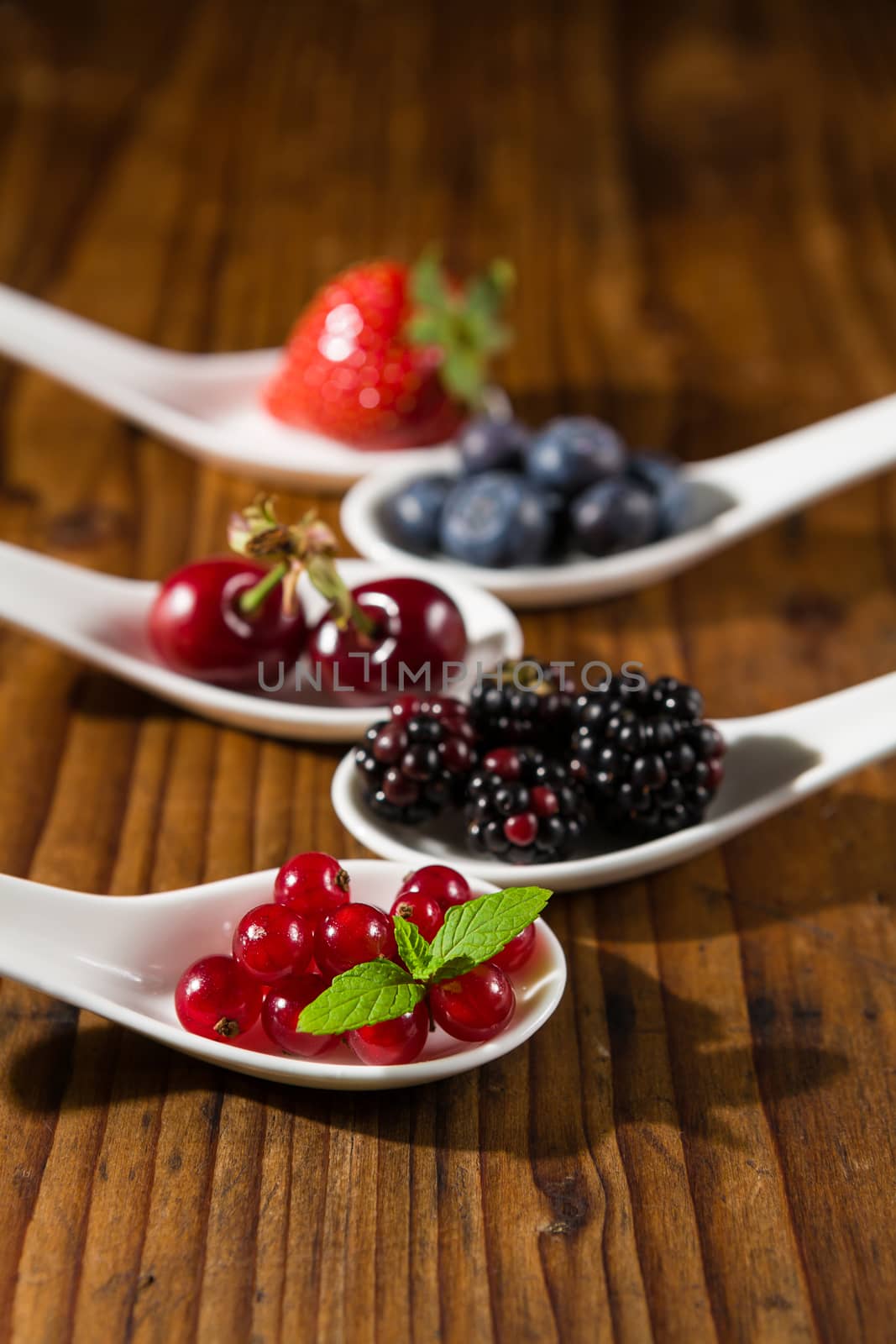 Closeup of collection of wild berries on white spoons by LuigiMorbidelli