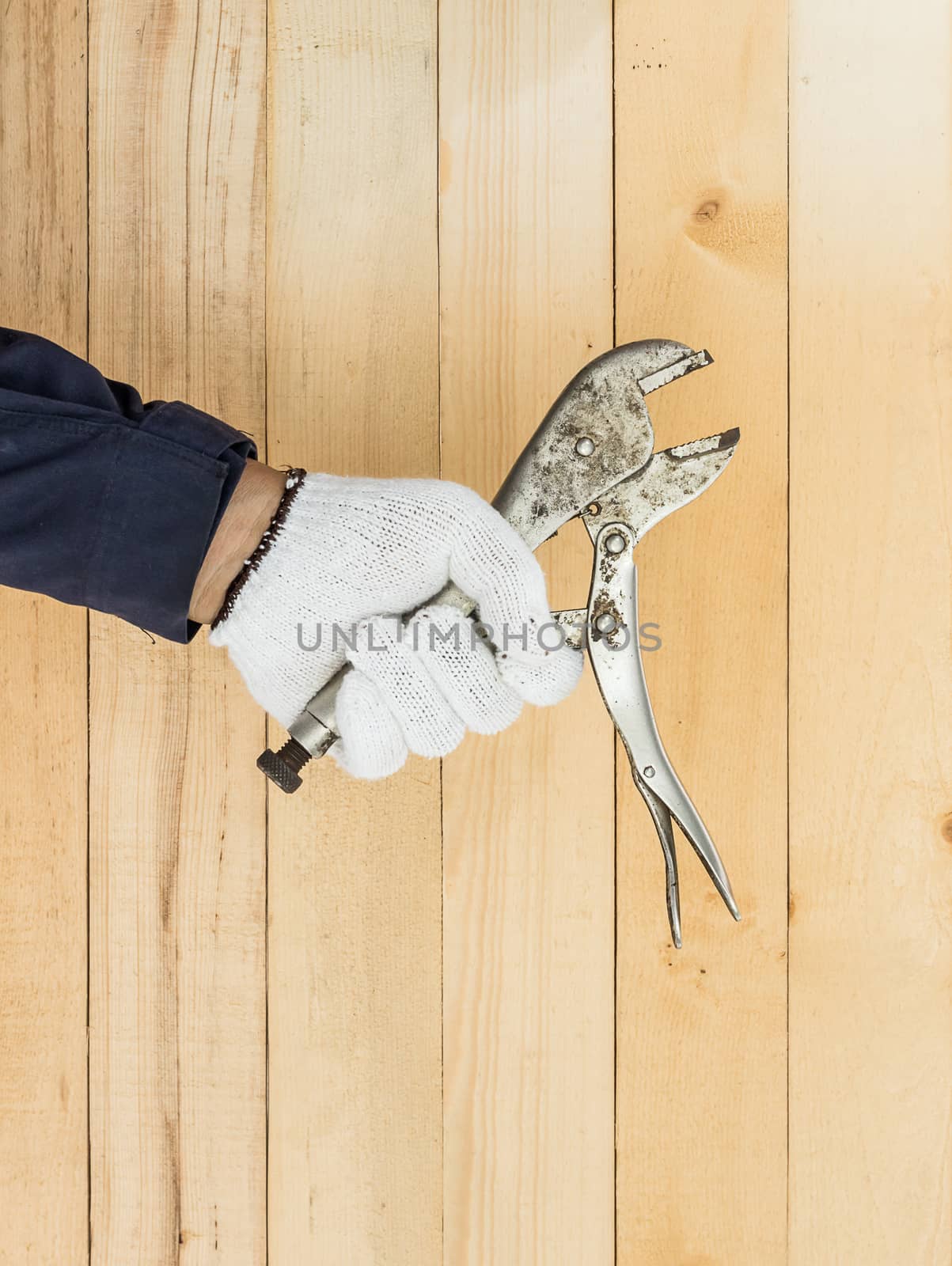 Working hand in glove holding a Adjustable wrench with wall wood background