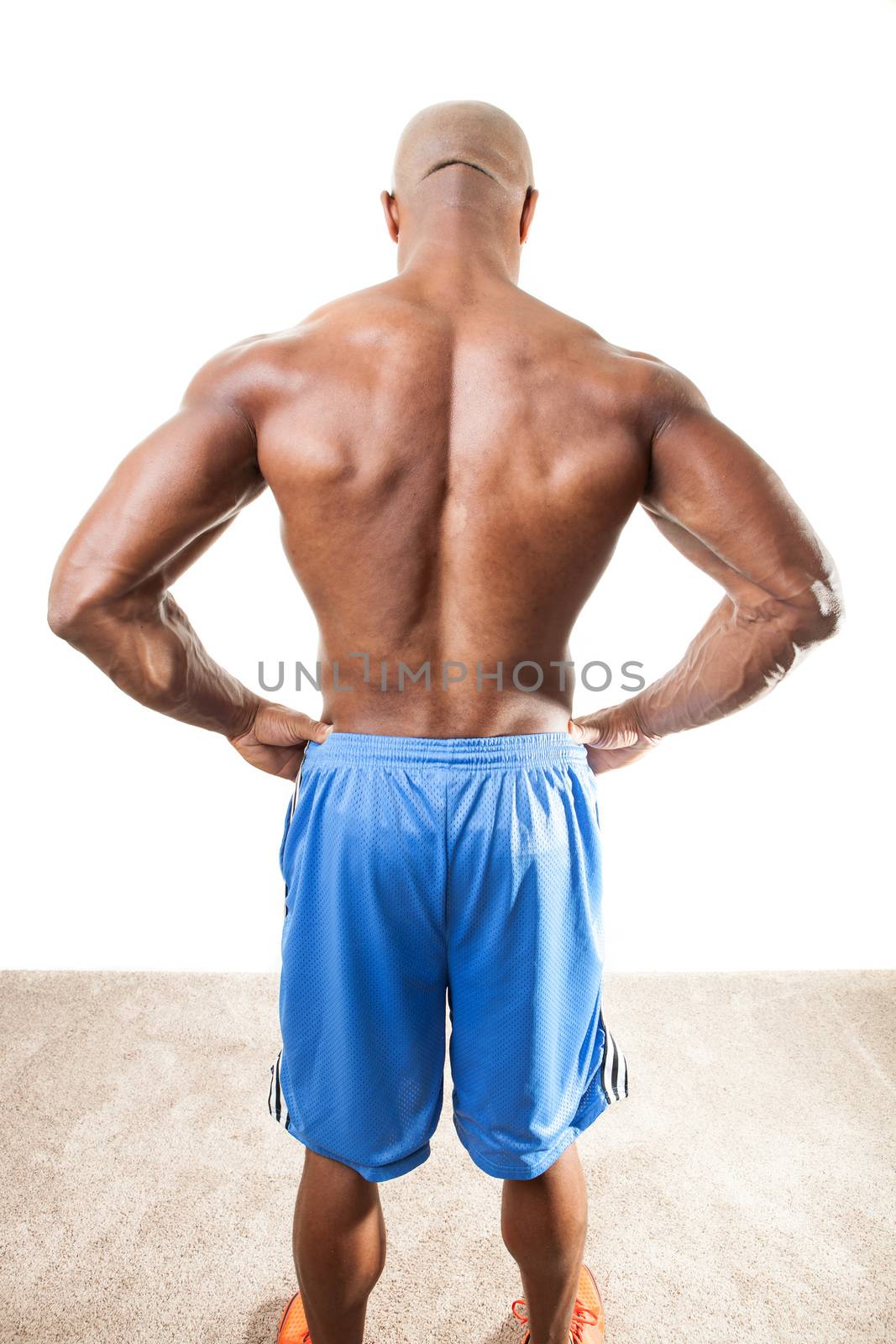 Toned and ripped lean muscle fitness man standing in front of a white background.
