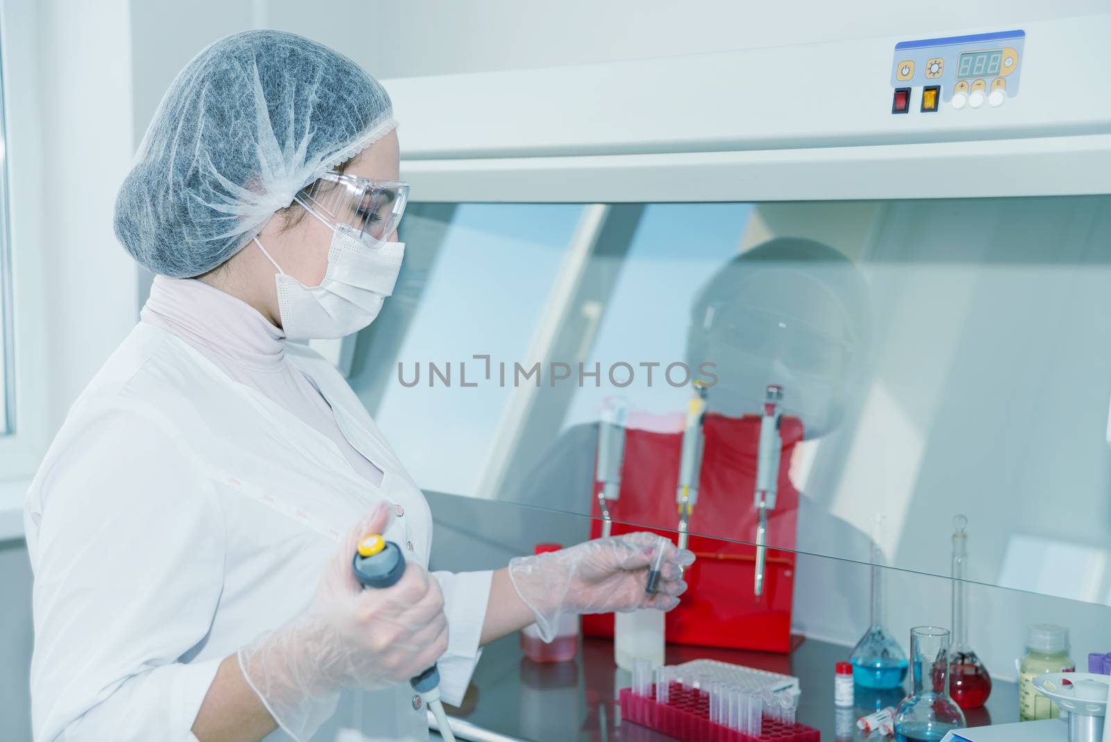 Woman scientist in a white protective clothing conducts research in a lab