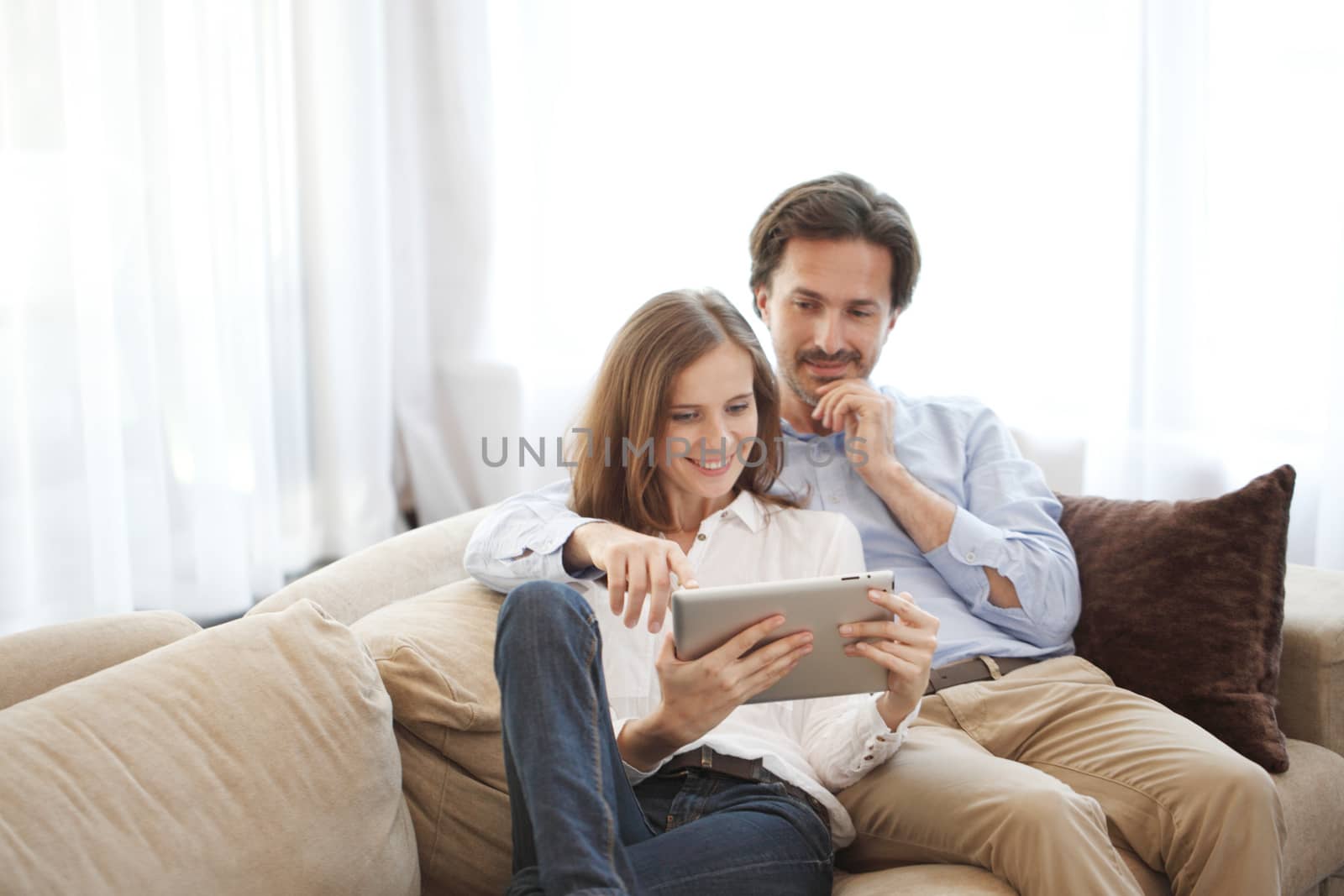 Cheerful couple using digital tablet at home