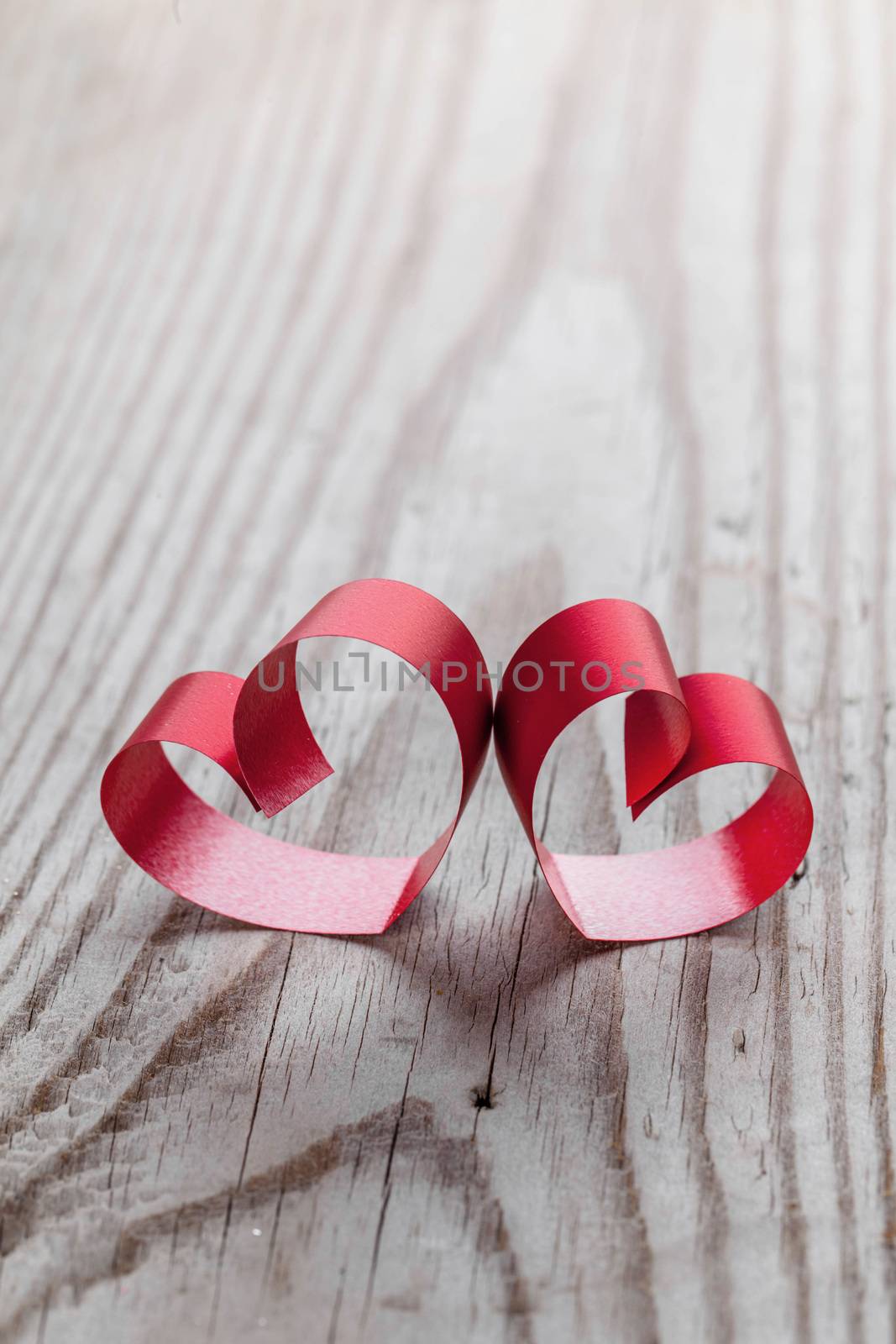 Two red small ribbon hearts on wooden background