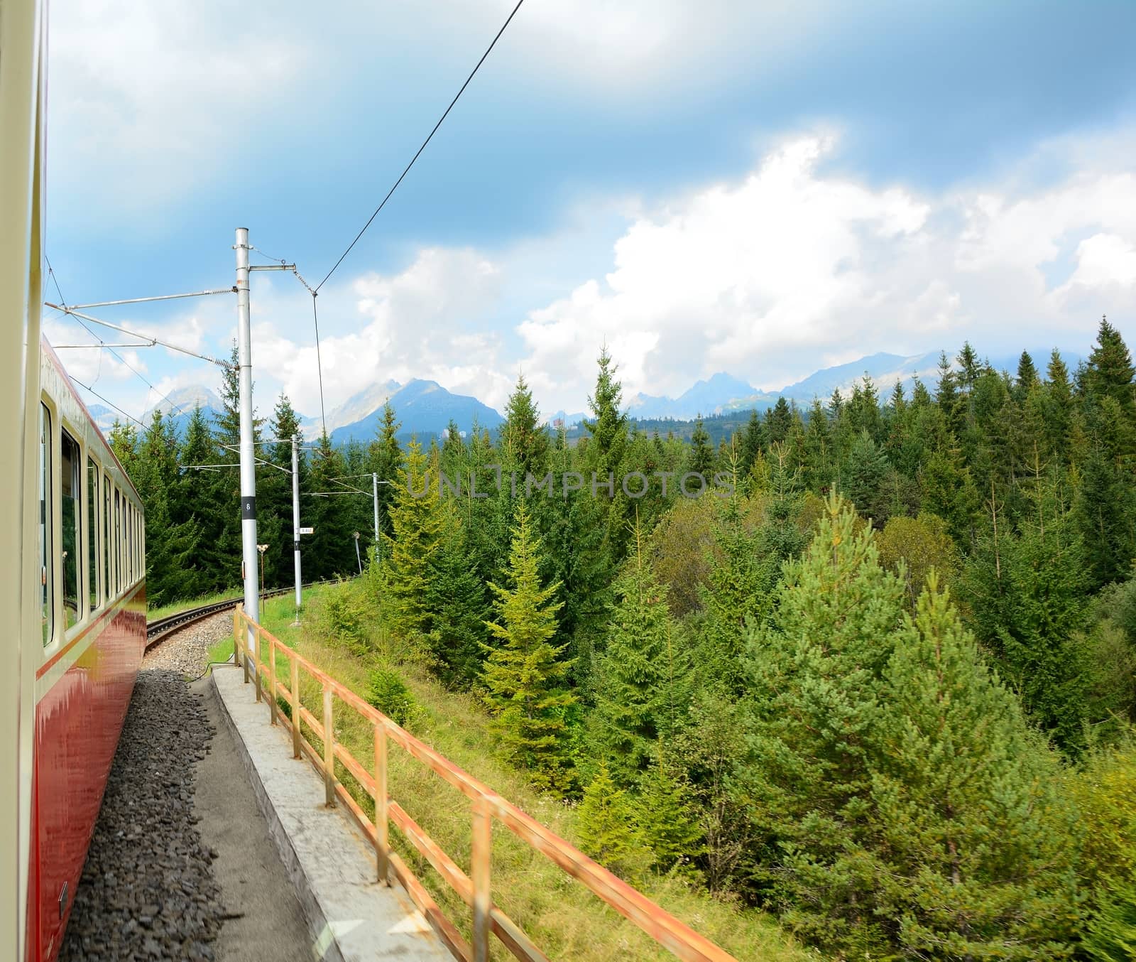 View of High Tatras mountains from window of speeding train on cog railway during way from Strba station to Strbske Pleso station.