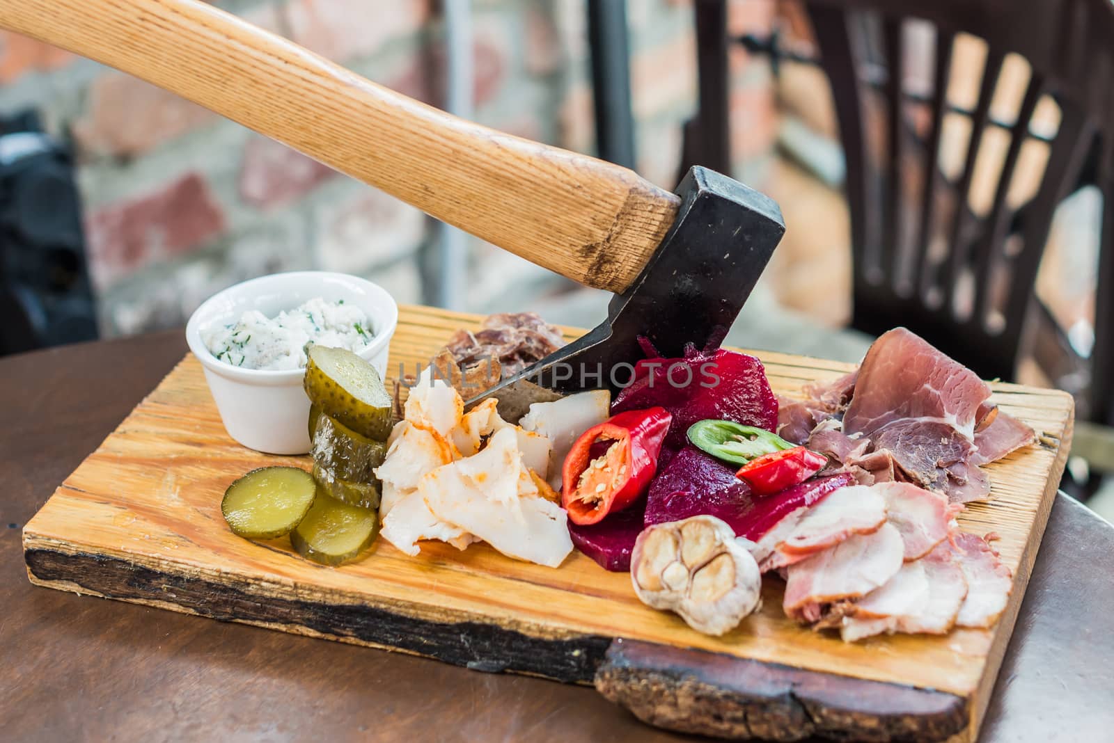 Slices fresh pork meat, lard on wooden board with vegetables, spices, stuck ax on the table