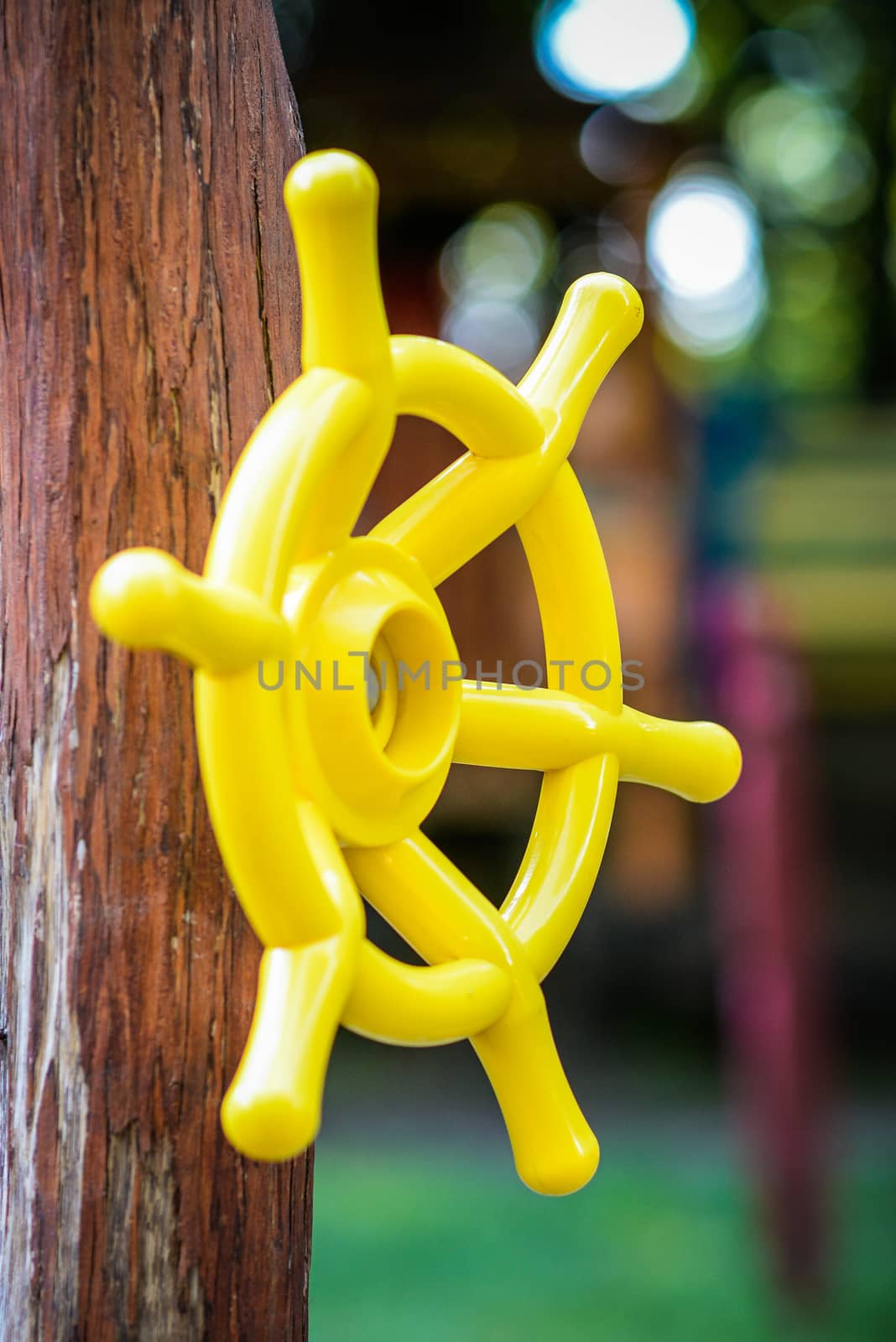 Yellow plastic children's handlebar of the ship a wooden girder on the playground
