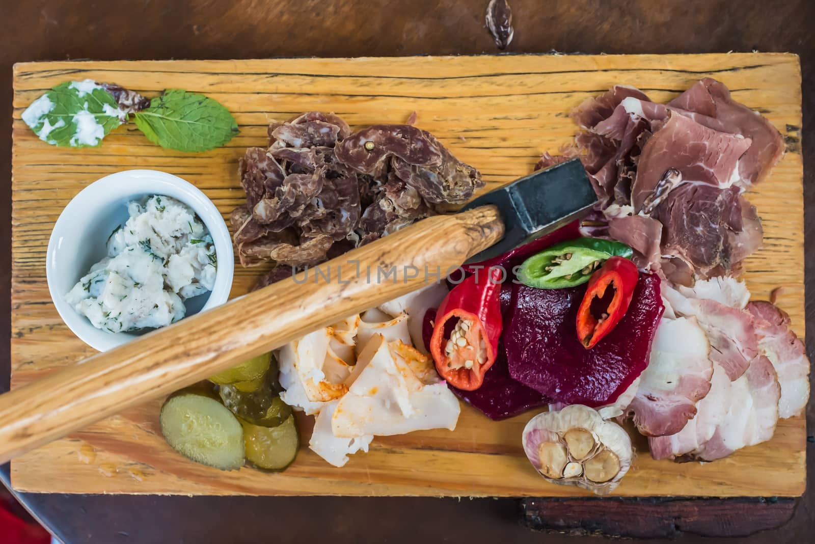 Slices fresh pork meat, lard on wooden board with vegetables, spices, stuck ax on the table