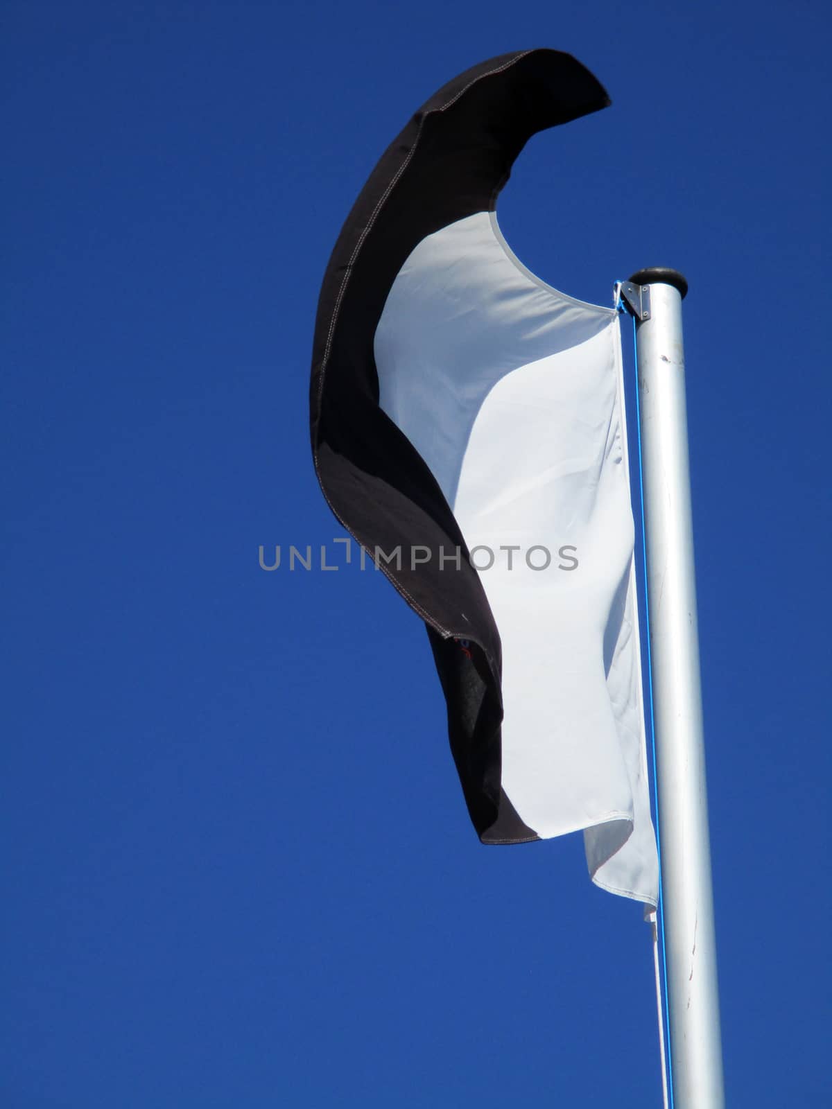 white and black flag flying in the blue sky